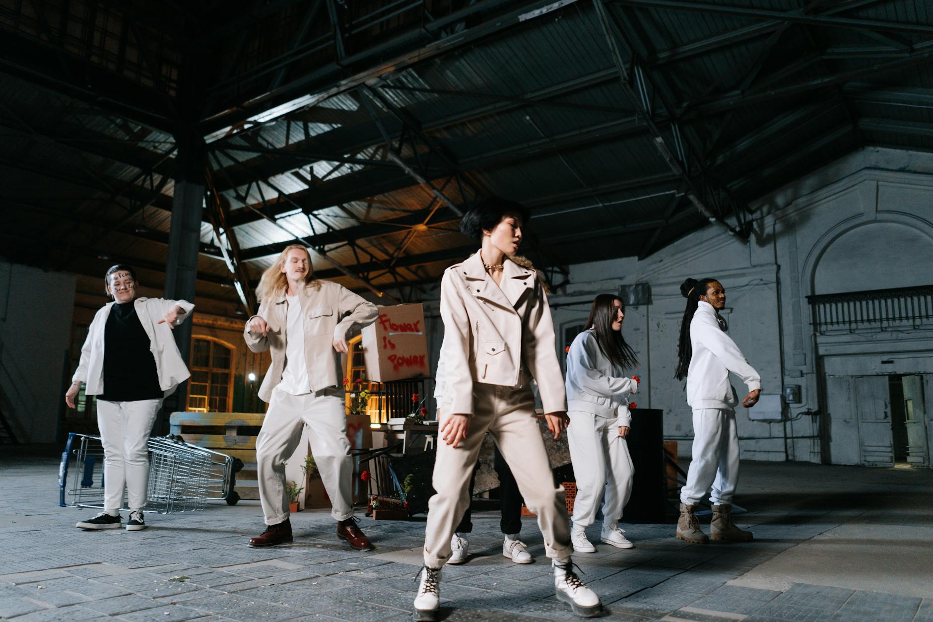 A diverse group of people stands in a warehouse, engaging in peaceful protest with signs advocating change.