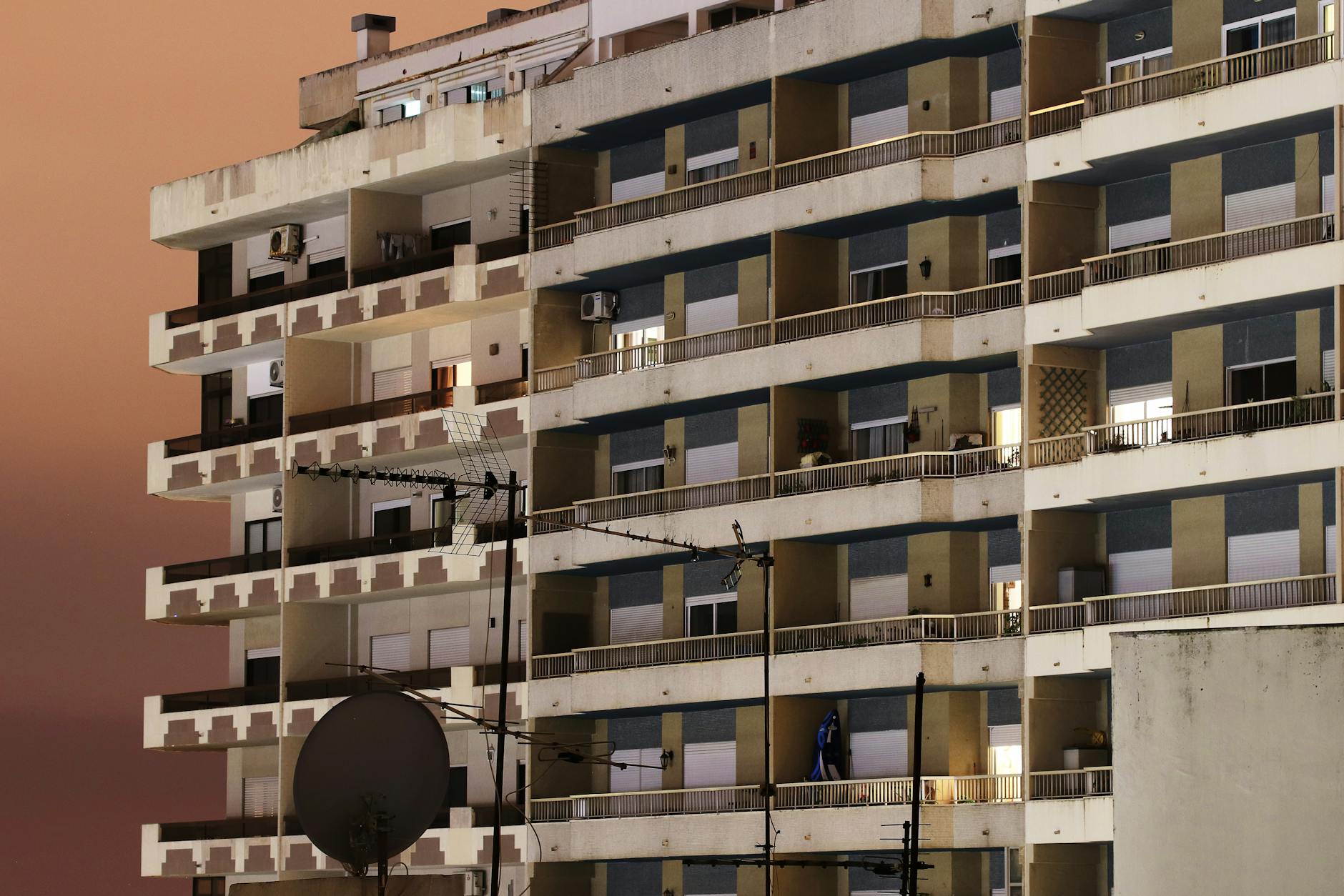 A modern residential building in Almada, Portugal, captured at dusk with a dramatic sky.