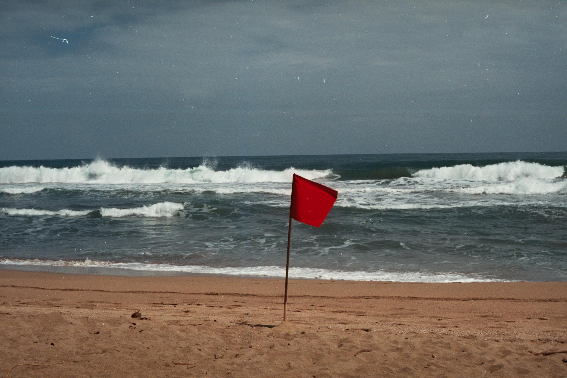 Avisos do IPMA: o que fazer e o que evitar (checklist de segurança para Lisboa) 6 A red flag signals dangerous conditions on a Costa Rican beach. Stay cautious.