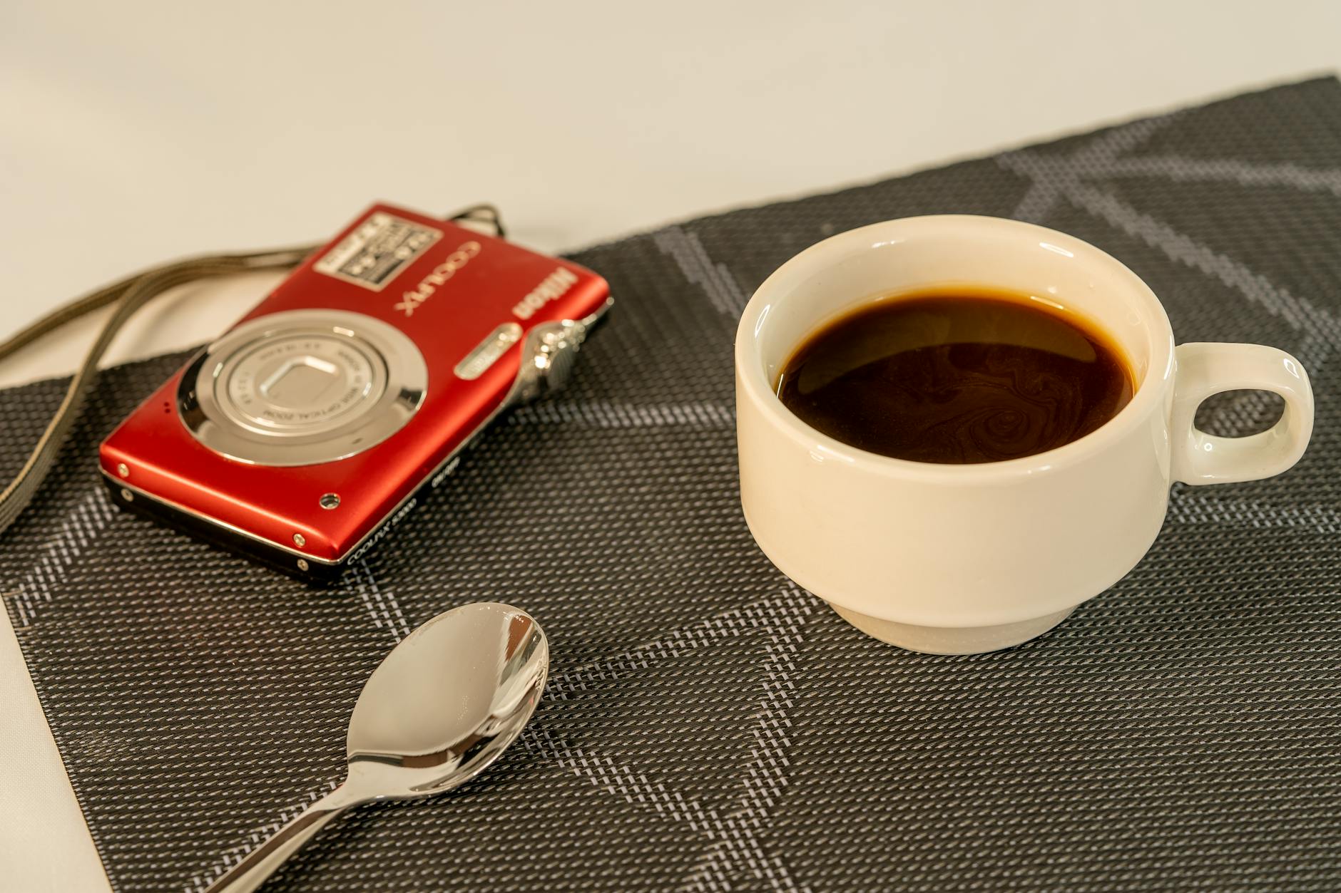 Cinema Em Lisboa: As Sessões Diferentes Que Não Aparecem Nos Outdoors 6 A white cup of coffee next to a red camera and spoon on a textured mat, perfect for stock use.