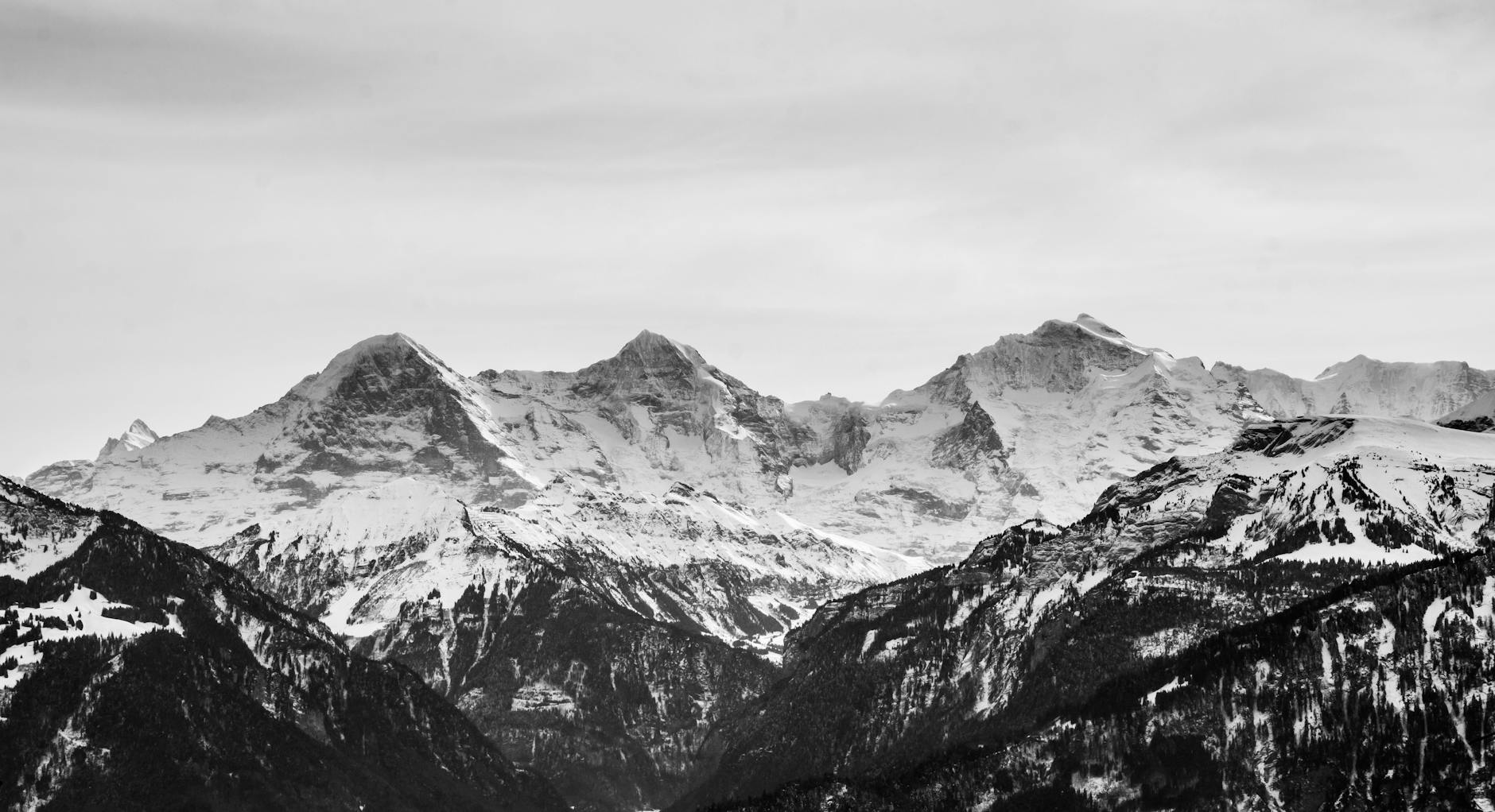 Peças De Teatro Em Lisboa: O Que Ver Se Só Podes Escolher Uma 4 Black and white photo capturing majestic, snow-capped mountains in a serene winter landscape.
