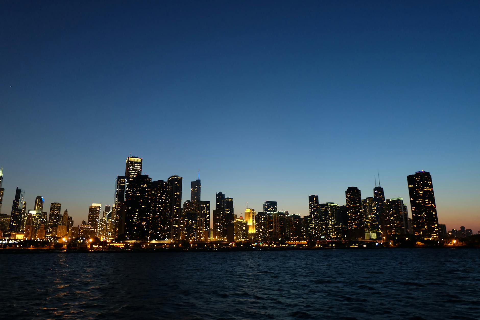 Caminhadas e miradouros com vento: decisões seguras para Lisboa e Sintra 4 Capture of Chicago's skyline at dusk with illuminated skyscrapers reflecting on Lake Michigan.