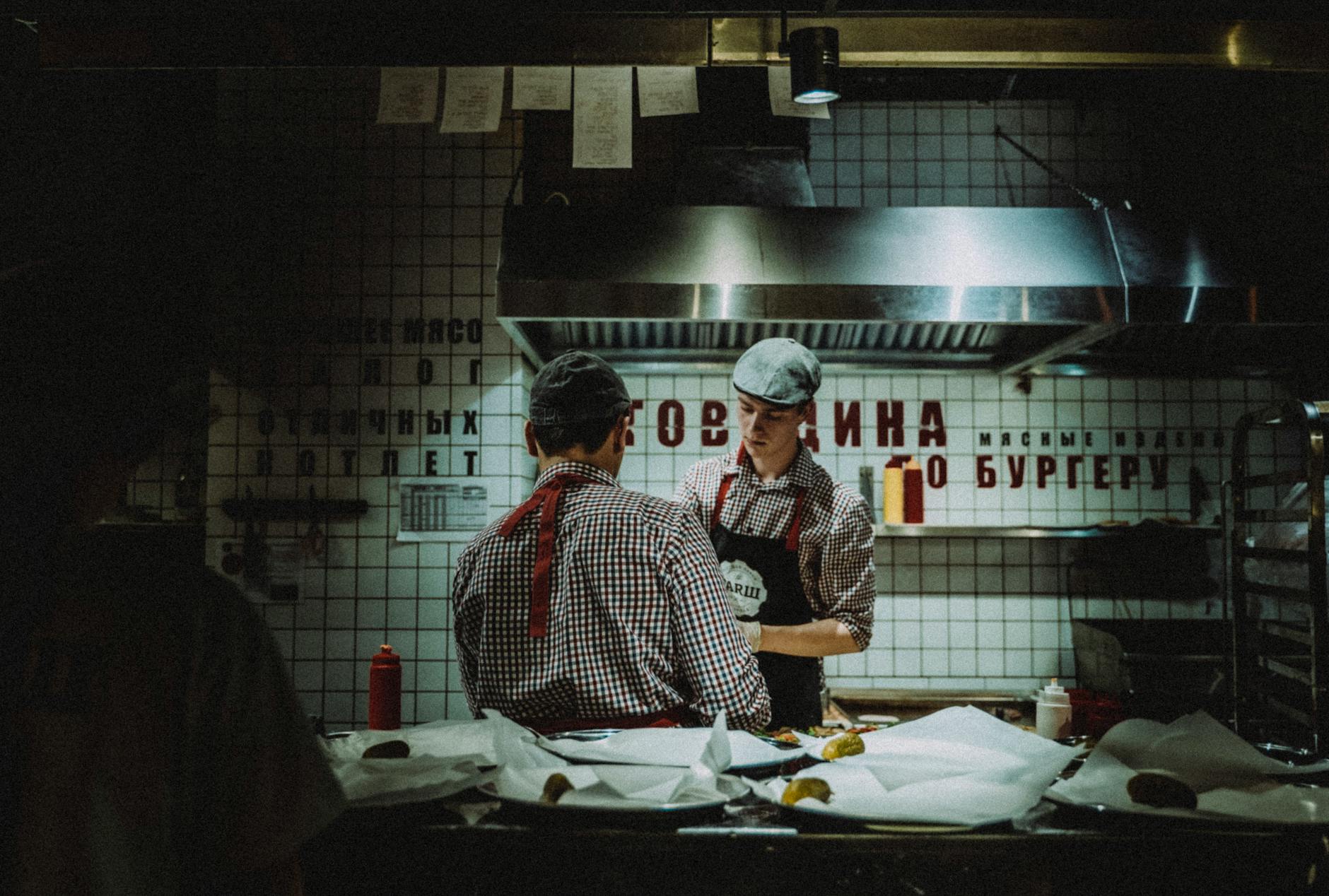 Restaurantes Bons E Baratos Em Lisboa: Onde Ainda Dá Para Jantar 5 Chefs working in dimly lit kitchen, preparing food. Atmosphere is rustic and industrial.
