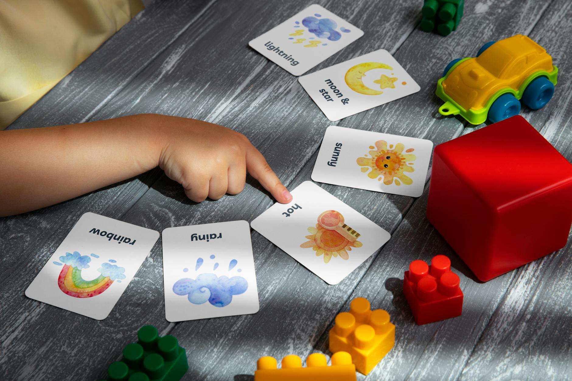 Kit essencial para aviso IPMA: o que ter à mão e quando adiar saídas (guia rápido) 7 Close-up of a child pointing at colorful educational flashcards and toys, promoting learning and creativity.
