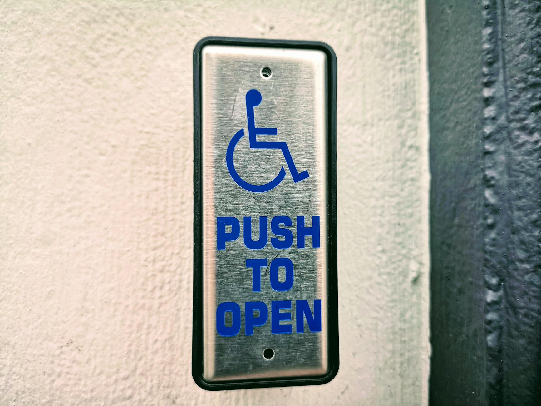 Peças De Teatro Em Lisboa: O Que Ver Se Só Podes Escolher Uma 5 Close-up of a push button sign for accessibility on a white wall.