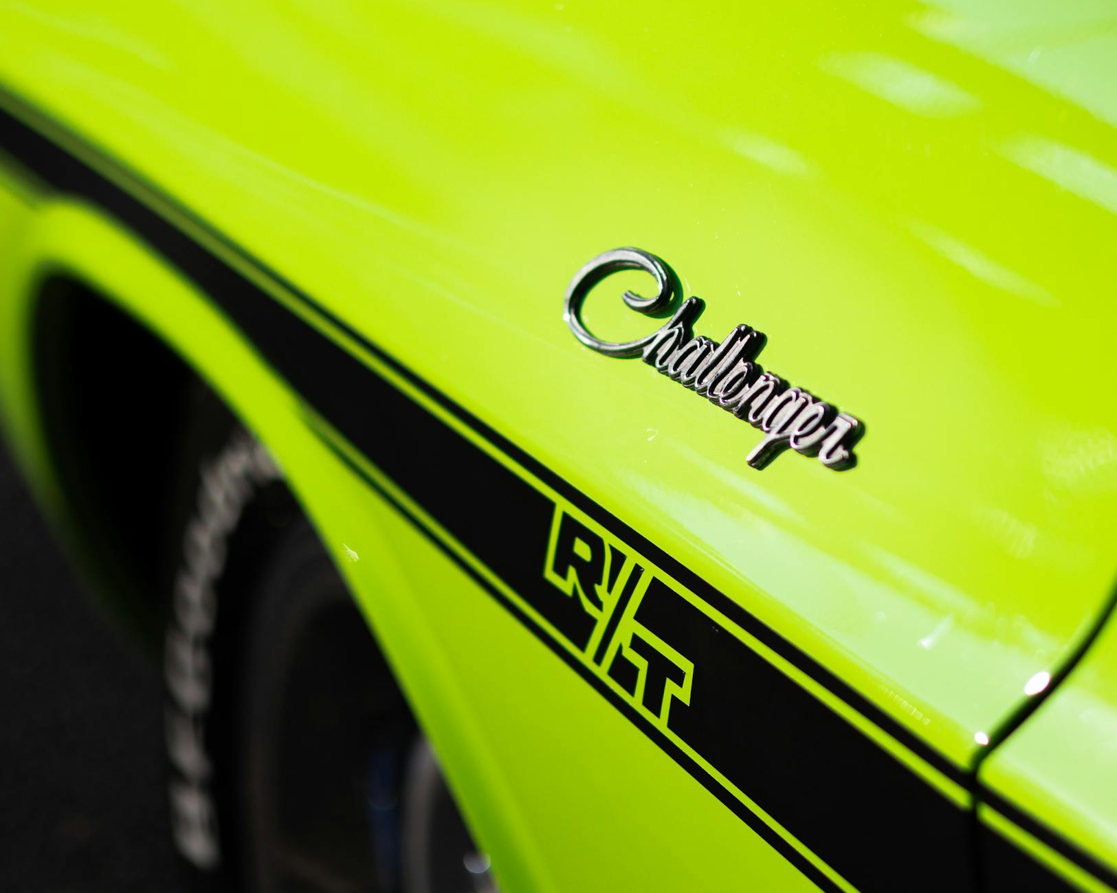 Close-up of a vibrant green Dodge Challenger RT emblem, showcasing retro design and dynamic style.