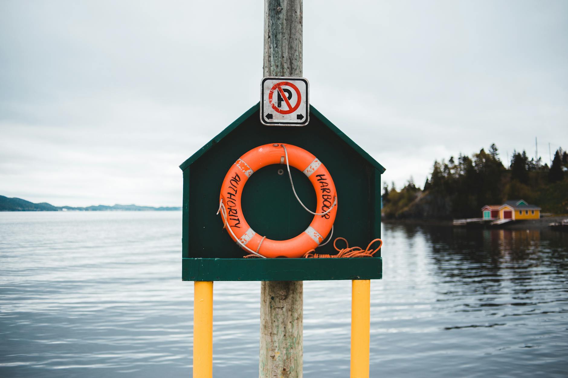 Colorful stand with red lifebuoy located on quay near peaceful rippling pond in countryside on cloudy day