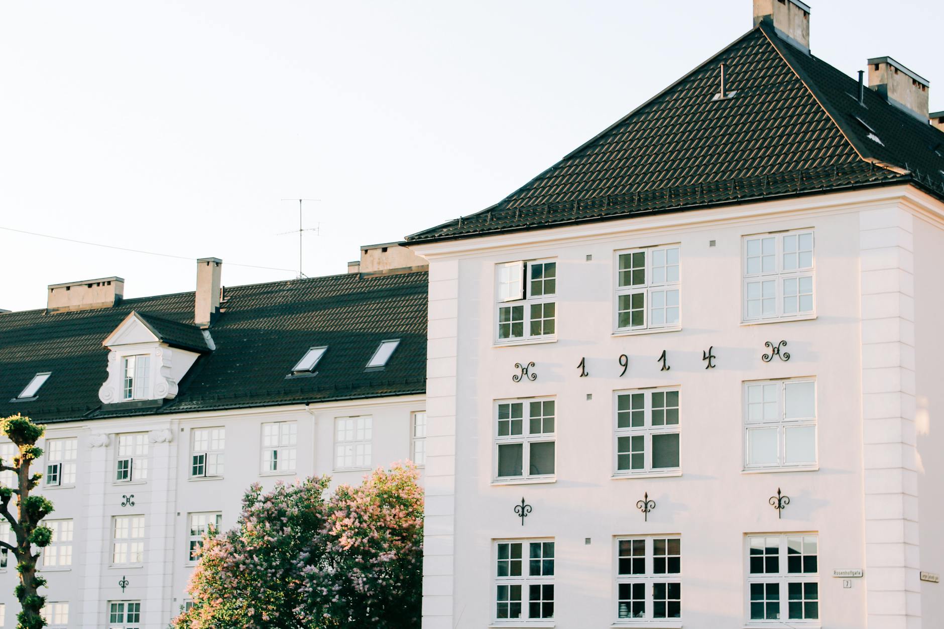 Facade of aged apartment building with white walls located in green area of town