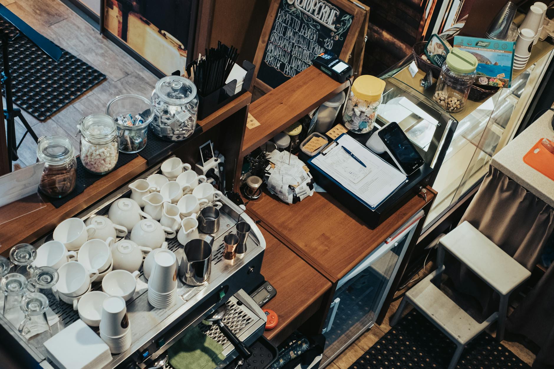 Overhead view of a café in Krasnodar, showcasing coffee cups, cash register, and cozy atmosphere.