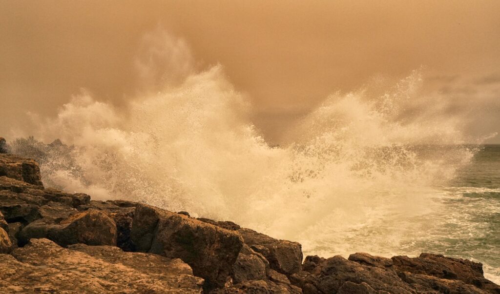 A large wave crashing over a rocky shore