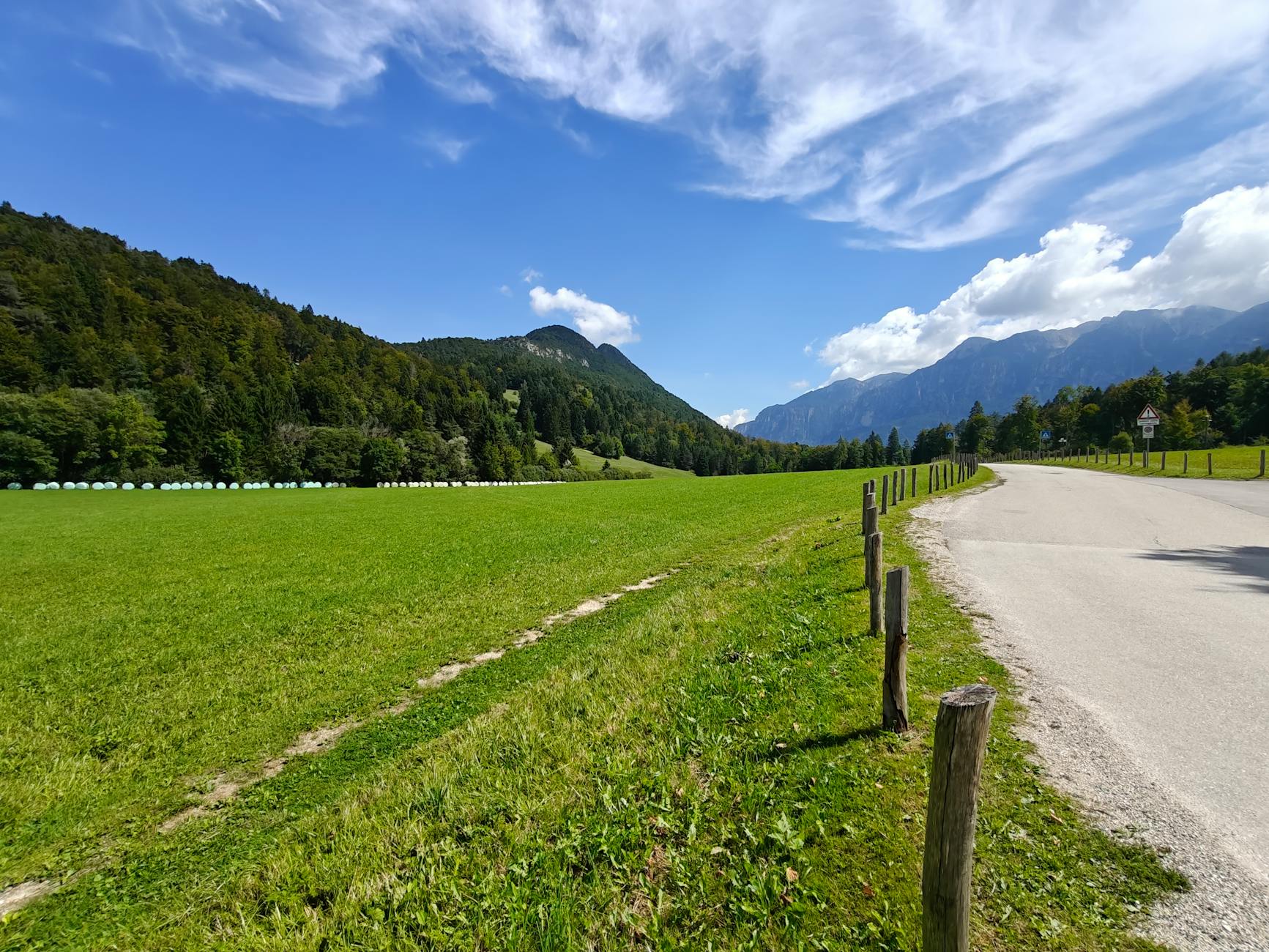 Picturesque landscape of lush fields and mountains in Trentino-Alto Adige, Italy, on a sunny day.
