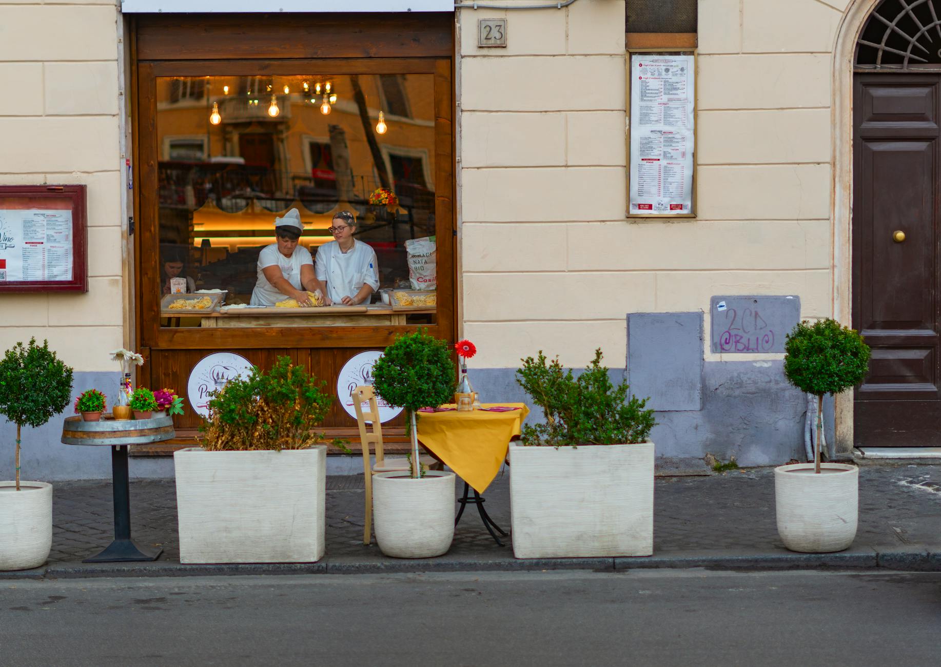 Street view of a cozy Italian bakery with chefs preparing food inside. Rome, Italy setting.