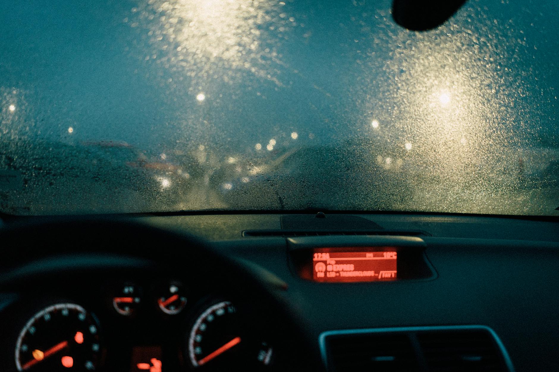 Aviso do IPMA em Lisboa: como proteger casa, janelas e varanda em 15 minutos 7 View from car interior with raindrops on windshield and blurred lights at night.