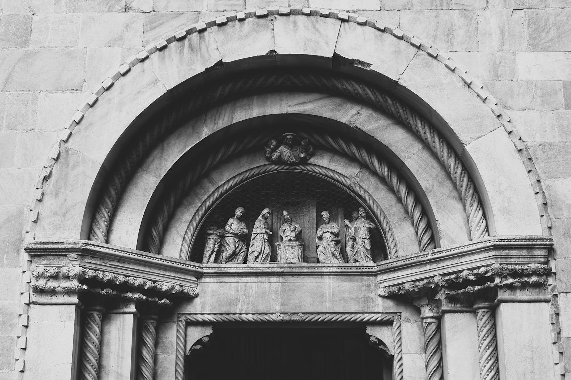 Exposições “free entry” em agosto: como escolher sem perder uma tarde à toa 6 A black and white photograph of the detailed entrance of Como Cathedral, showcasing artistic stone sculptures.