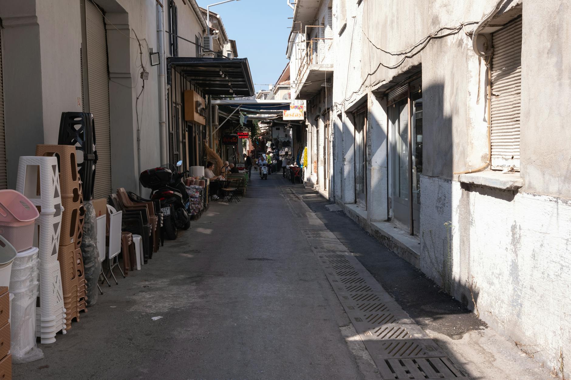 A bustling alley in Kemeraltı Bazaar with shops and people on a sunny day in İzmir, Türkiye.