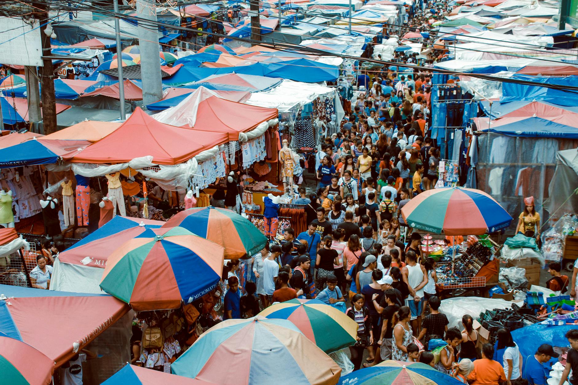 A bustling street market in Manila with colorful tents and a lively crowd shopping outdoors.