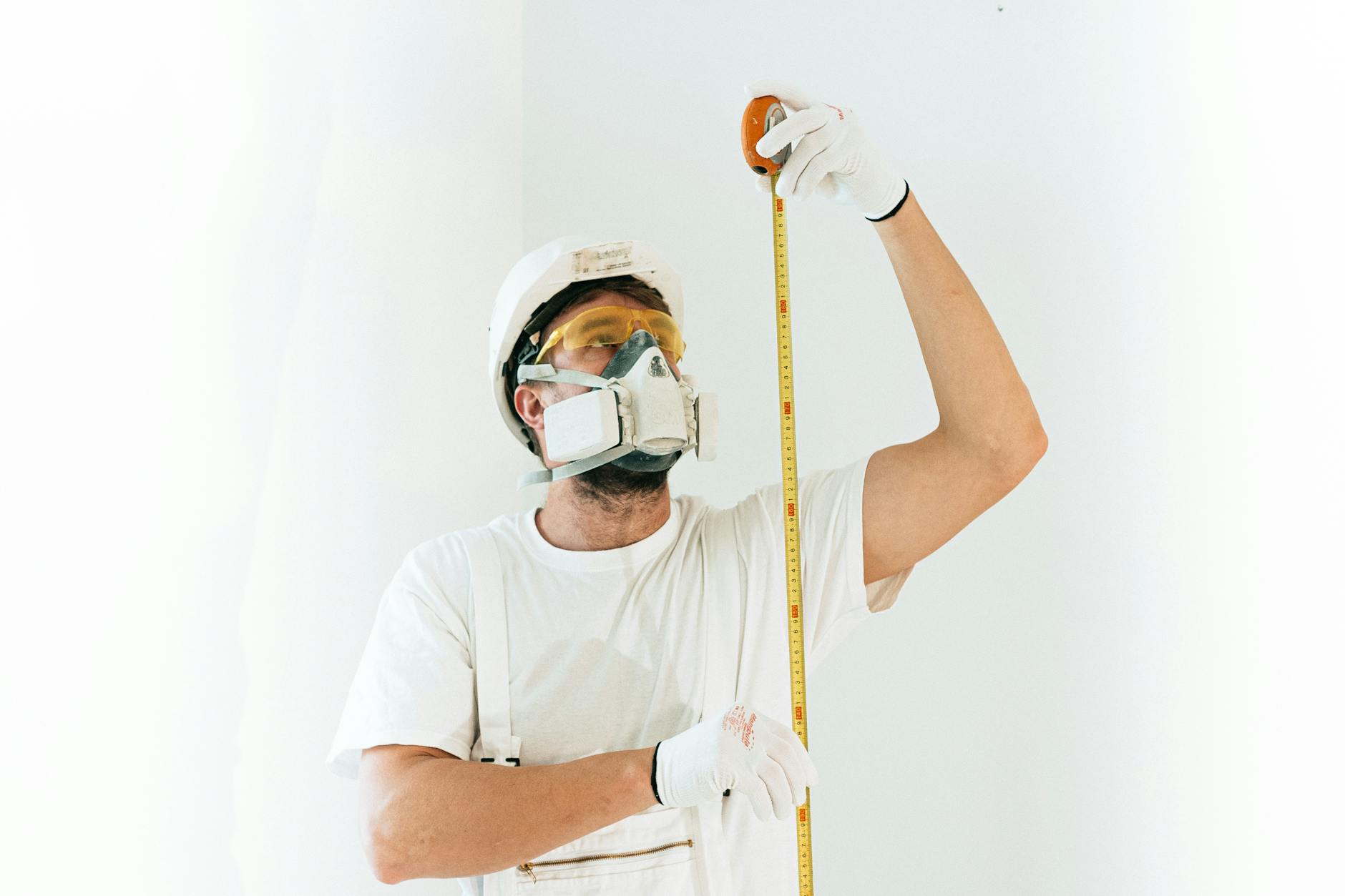 Diferença entre cheias naturais e cheias provocadas por descargas de barragens 7 A construction worker wearing safety equipment measures with a tape against a light background.