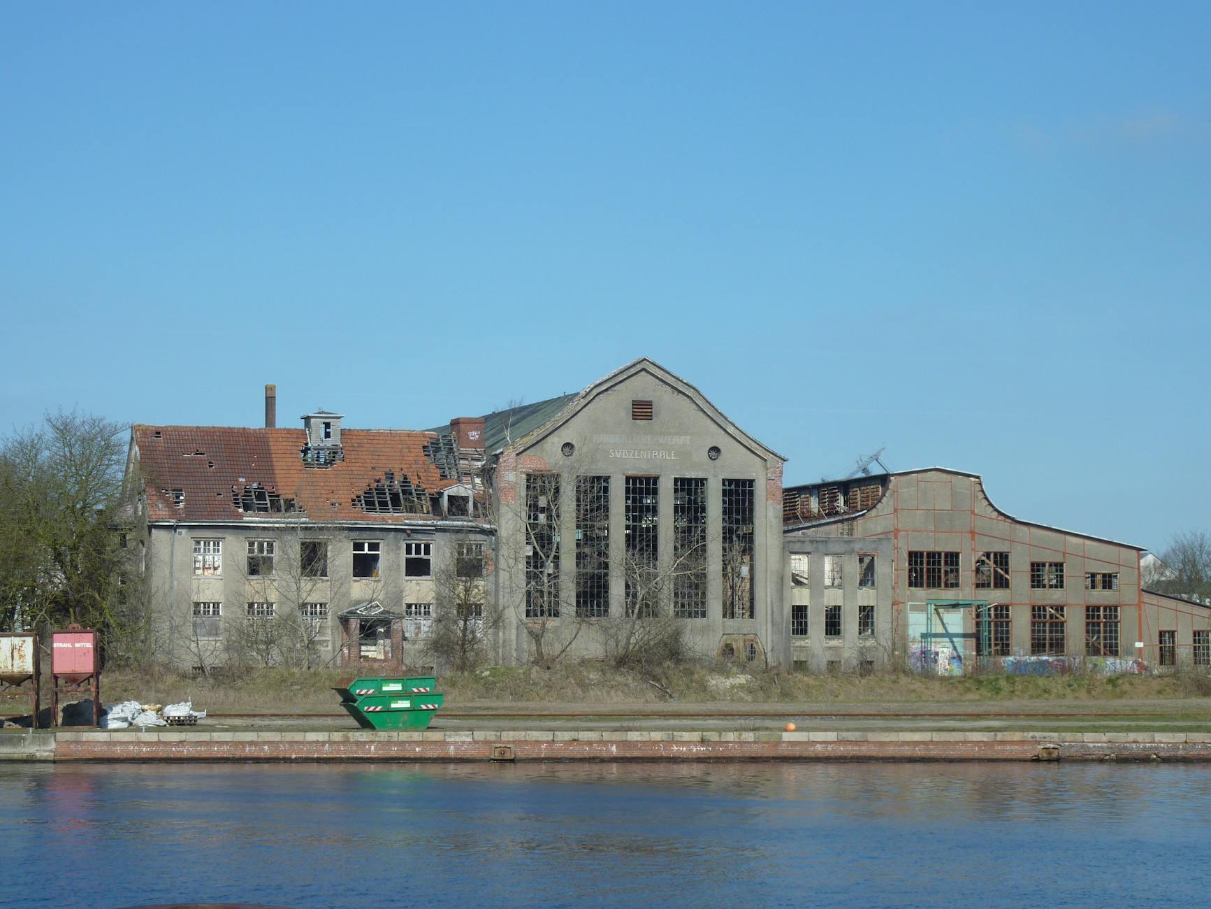 A deserted industrial building by a waterway, showcasing urban decay.