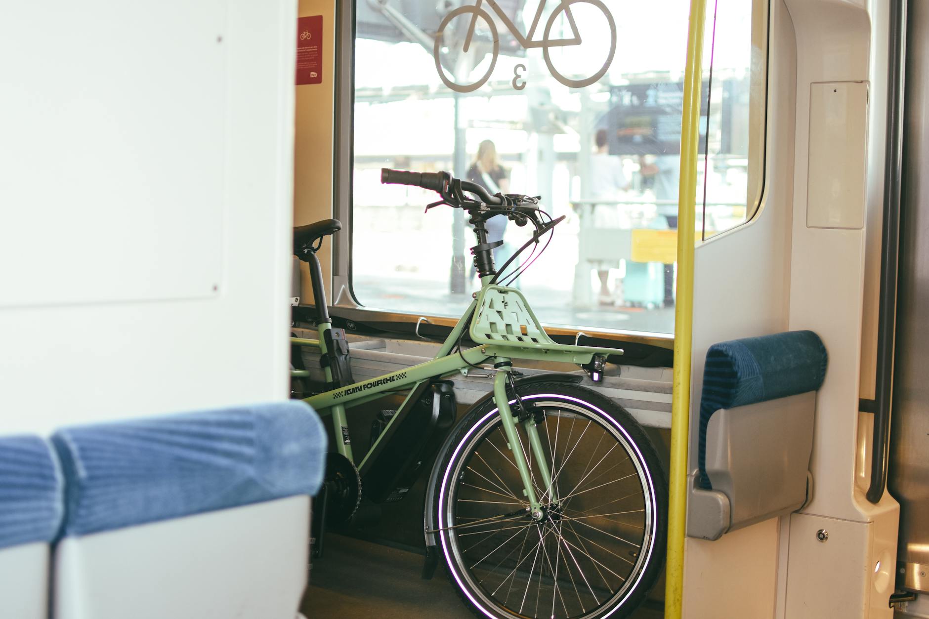 A green bicycle inside a train, seen through a window, in Bordeaux, France.