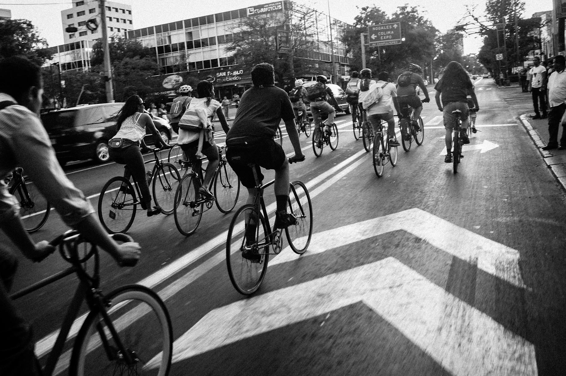 A group of cyclists ride down a city street, showcasing urban biking culture.