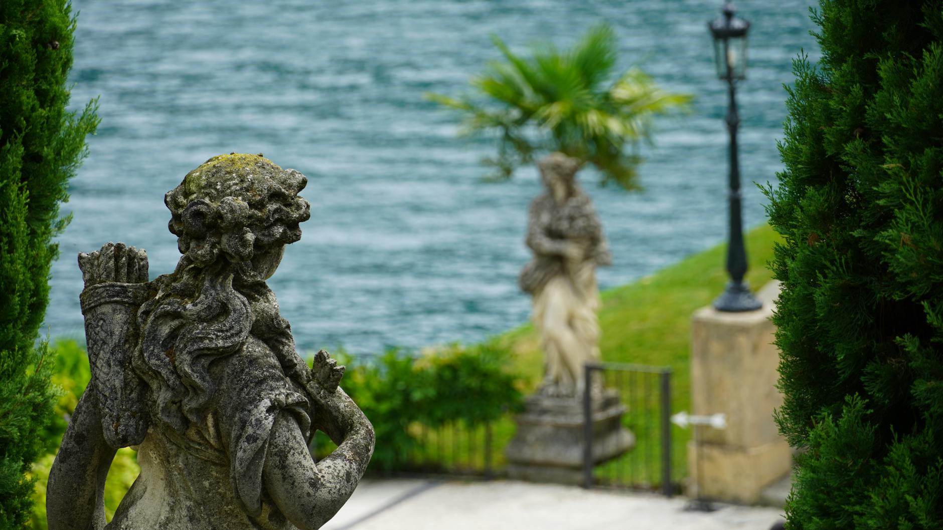 Street art: como tirar boas fotos sem parecer uma sessão gigante 7 A serene view of ancient statues and lush greenery by Lake Como, Italy.