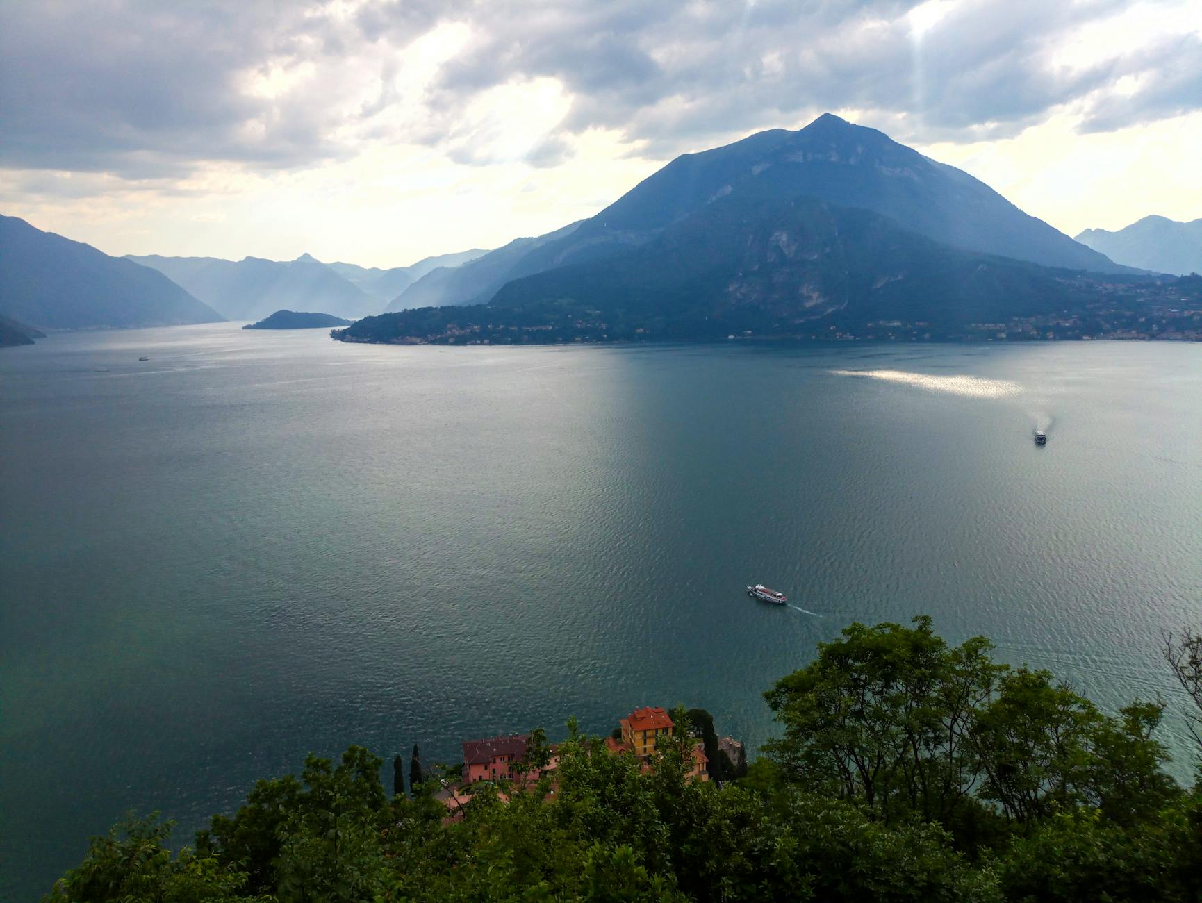 Festival dos Oceanos: concertos e atividades grátis — como descobrir as melhores 7 A serene view of Lake Como in Italy with mountains and boats under cloudy skies.