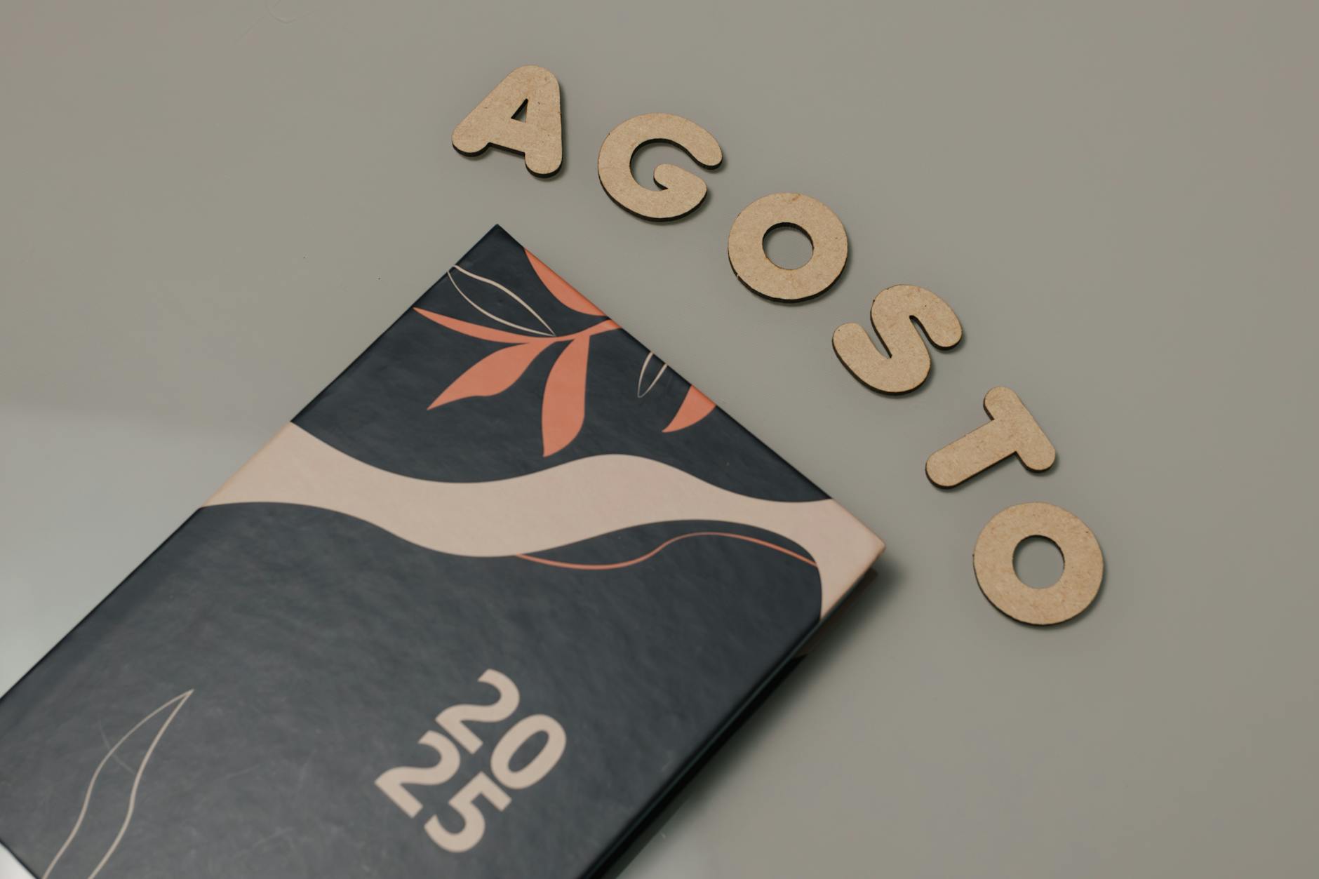 “Hoje quero sair mas não quero gastar”: 30 ideias em Lisboa para agosto 9 A stylish 2025 planner with artistic cover design and 'Agosto' letters on a flat surface.