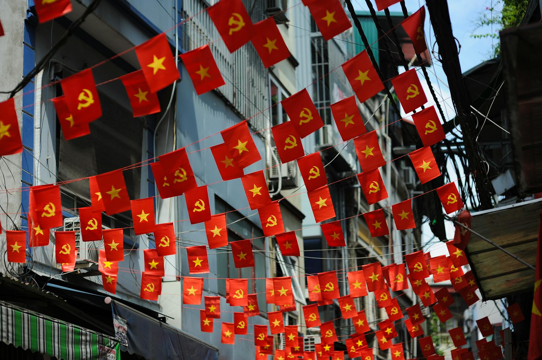 A vibrant scene of red flags with yellow stars hung across an urban street, creating a festive feel.