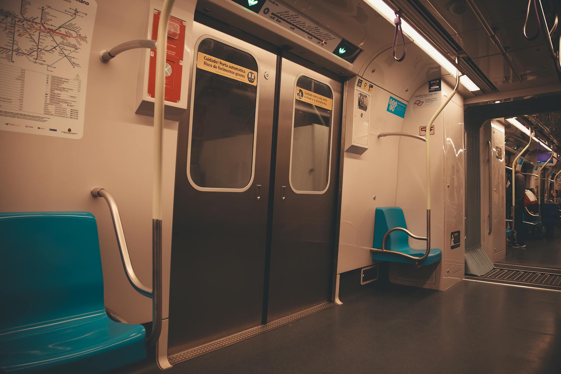 A view of an empty São Paulo metro car, showcasing blue seats and steel doors.