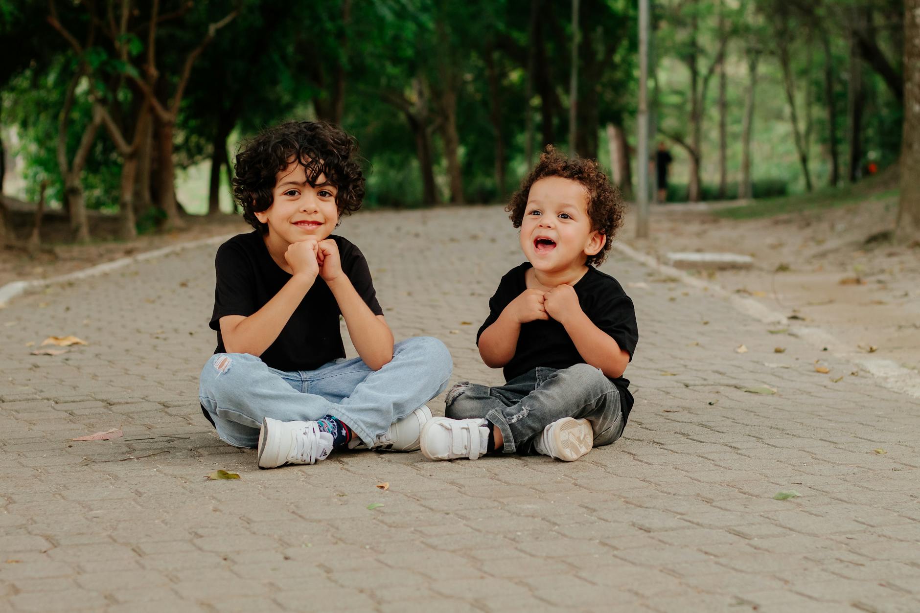 Adorable brothers sitting on a park path in São Paulo, Brazil, enjoying a joyful moment outdoors.