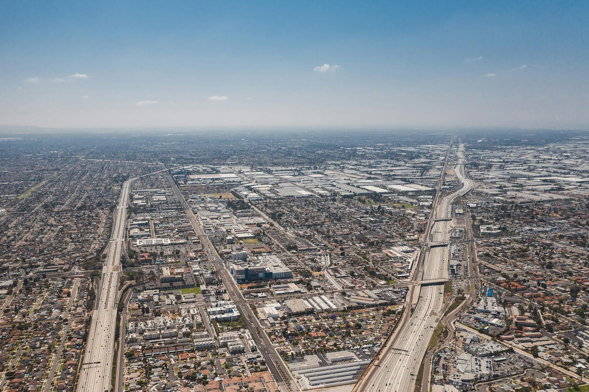 Diferença entre cheias naturais e cheias provocadas por descargas de barragens 4 Aerial shot capturing the vast urban expanse and highways of Los Angeles under a clear blue sky.