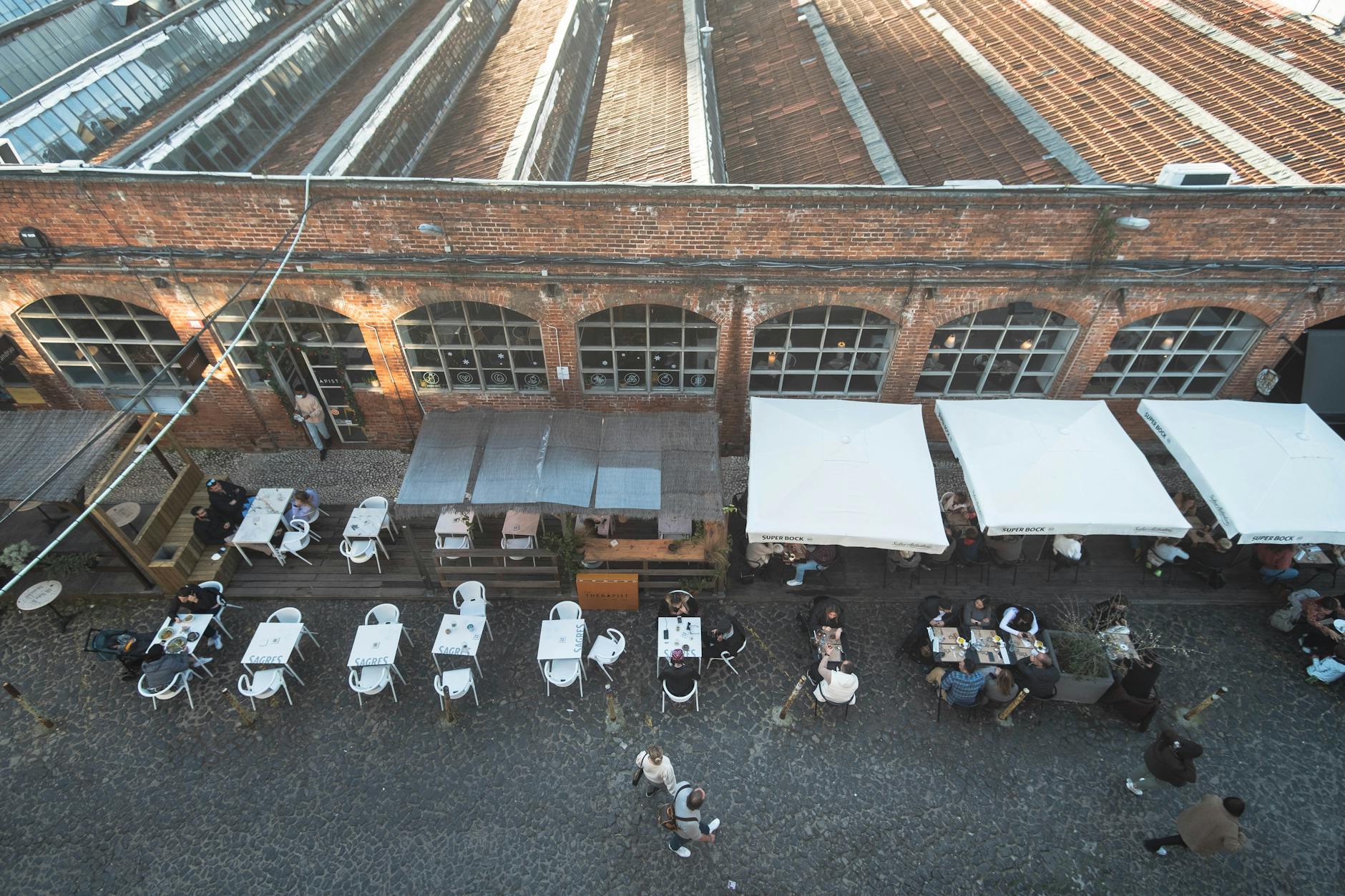 Aerial view of bustling outdoor dining at LX Factory, Lisbon. Perfect mix of industrial charm and social ambiance.