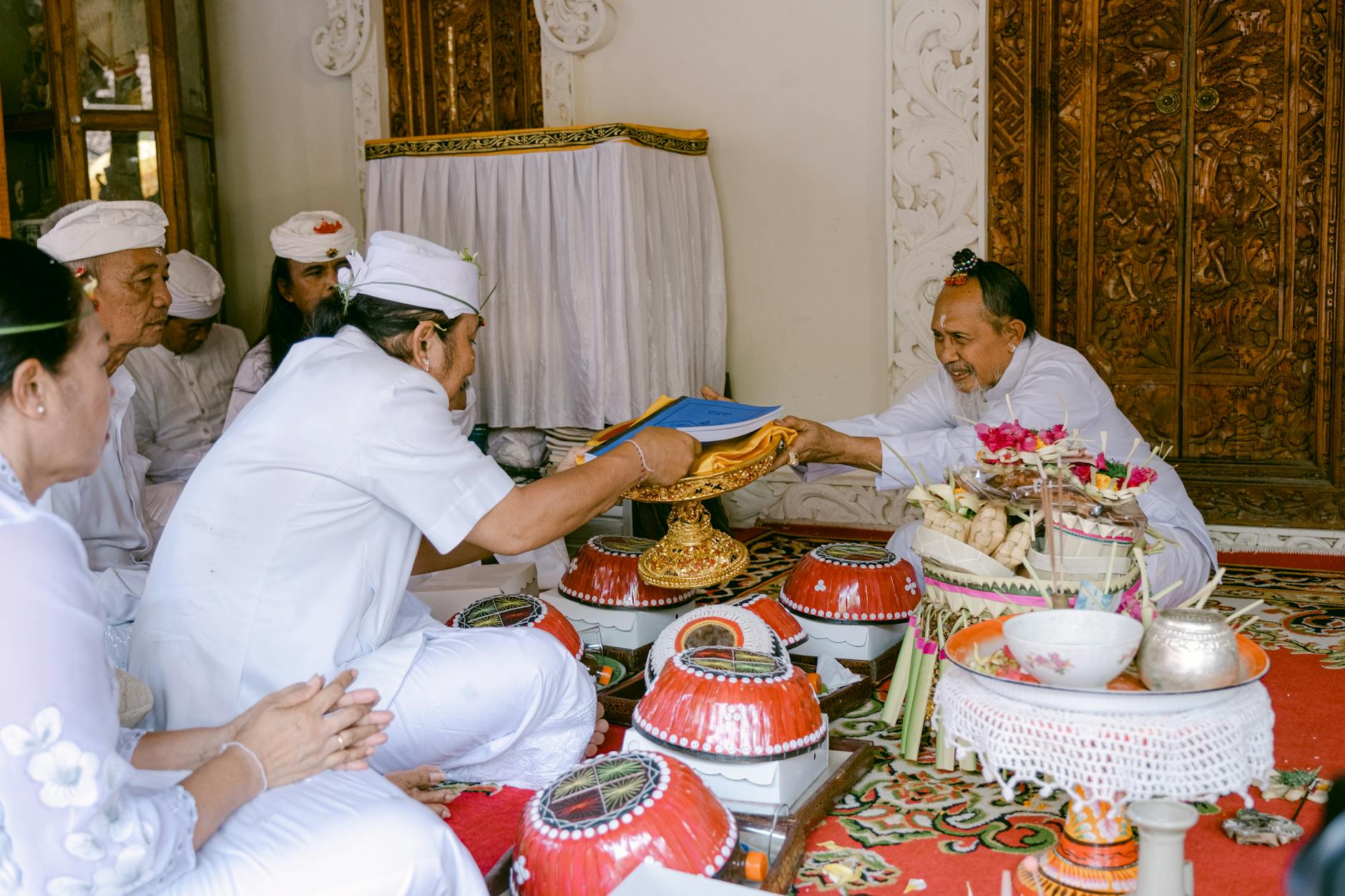 Balinese people in traditional attire during a ceremonial ritual with offerings in a temple.