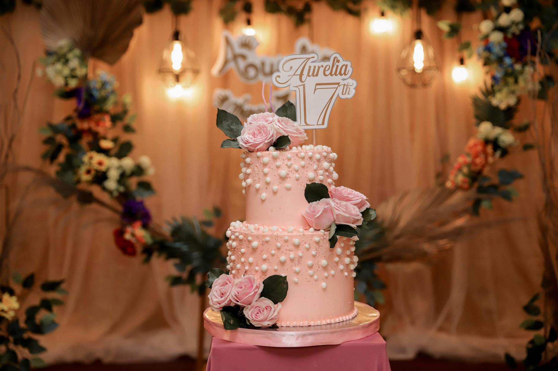 Planos Para Aniversário Em Lisboa: Onde Celebrar Sem Ser Caro 4 Beautiful pink two-tier birthday cake adorned with roses and pearls, perfect for celebrations.