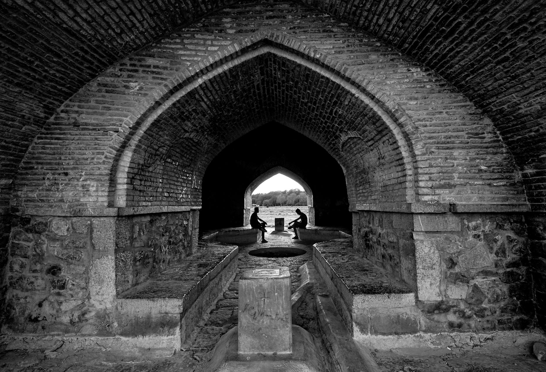 Black and white photo of Si-o-se-pol Bridge passage in Isfahan, Iran, highlighting its arched architecture.