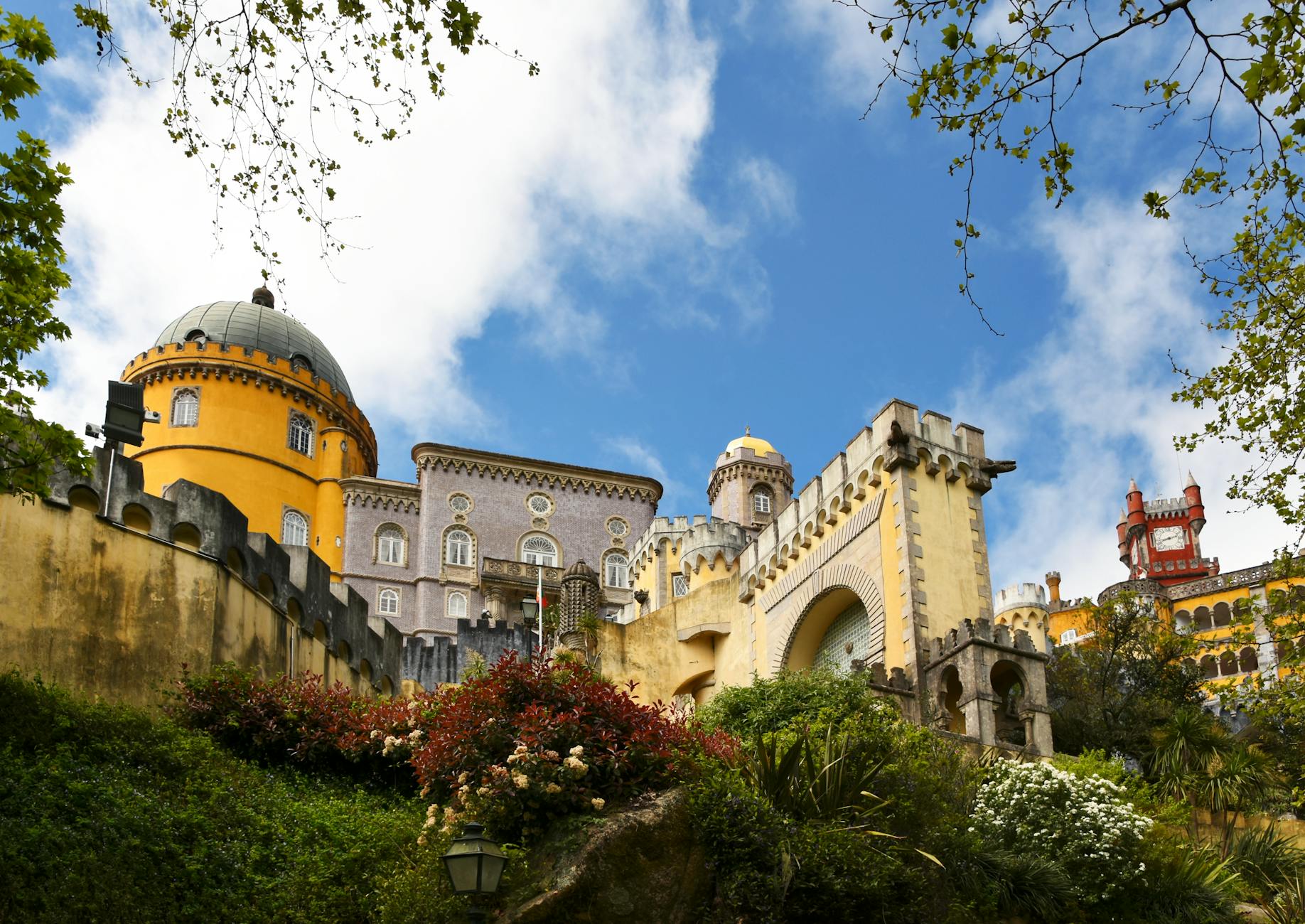 Breathtaking view of the colorful Pena Palace in Sintra, Portugal surrounded by lush greenery and clear skies.