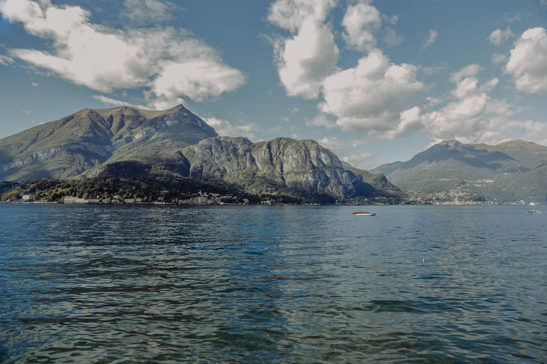 Breathtaking view of Lake Como bordered by lush mountains and calm waters under a bright sky.