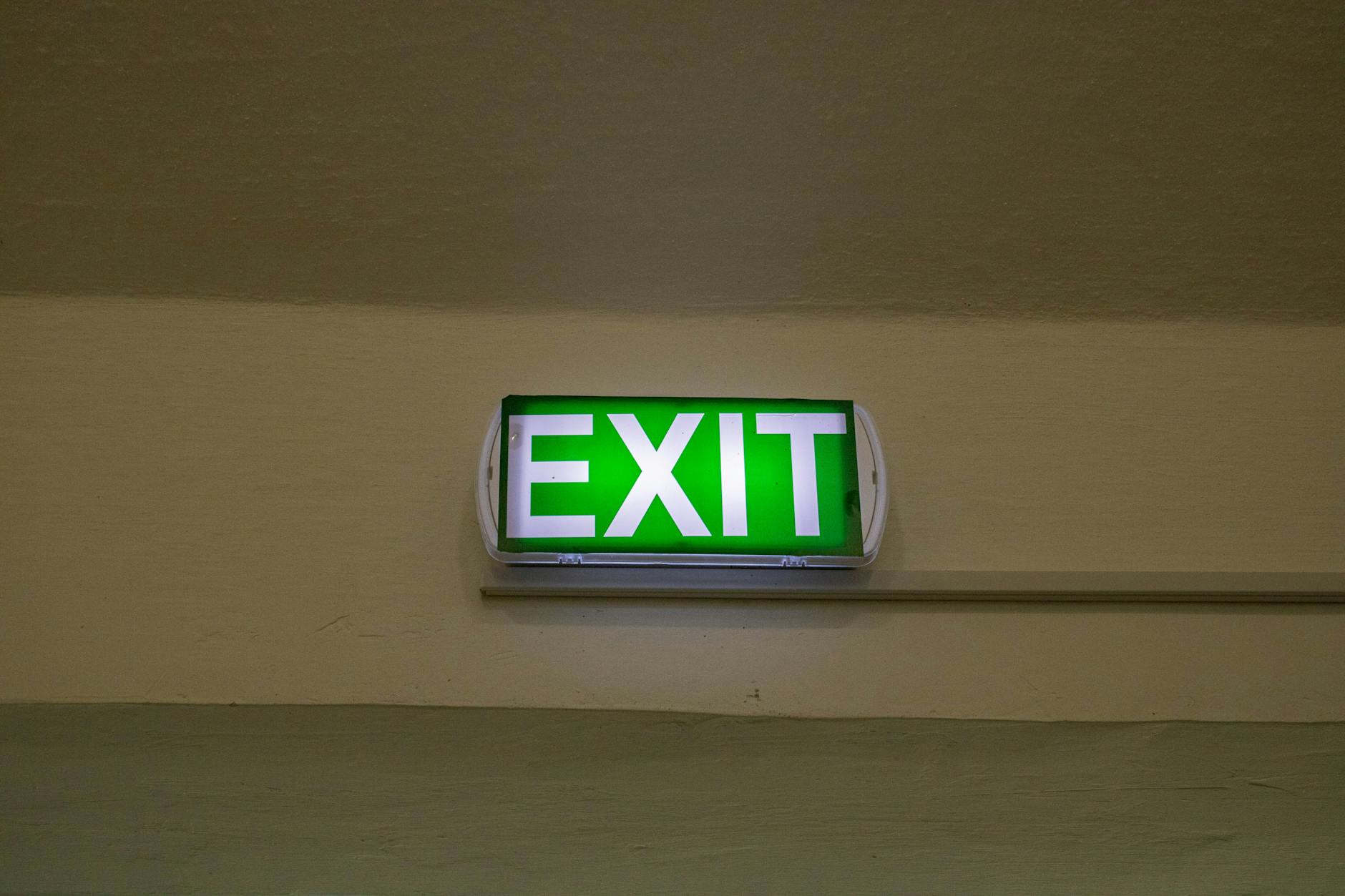 Bright green exit sign mounted on a hallway wall, offering clear direction for emergency evacuation.