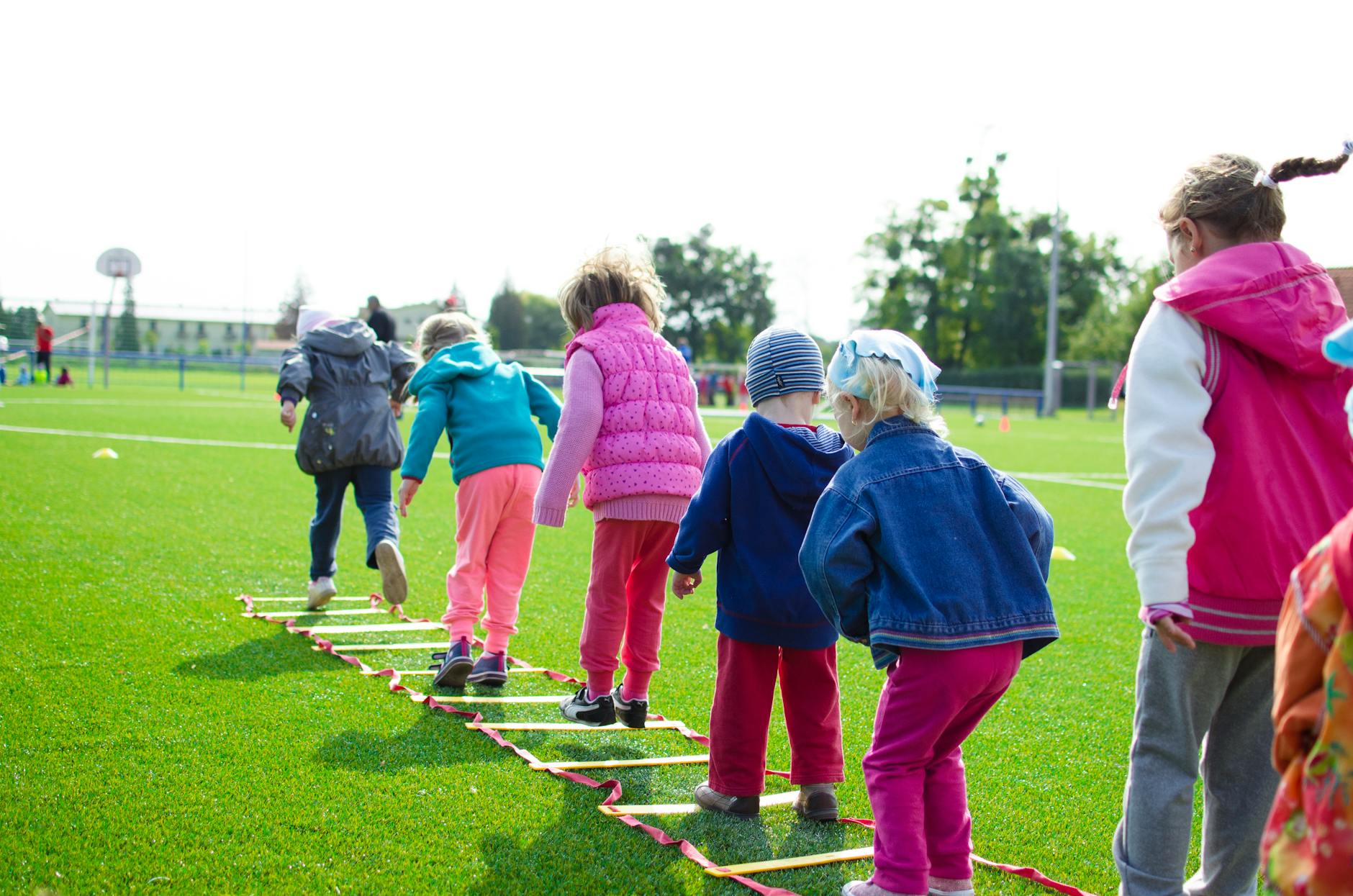 Festival dos Oceanos: ainda dá para apanhar em agosto? o que procurar 4 Children enjoy an outdoor activity on a grassy field, stepping over a ladder.