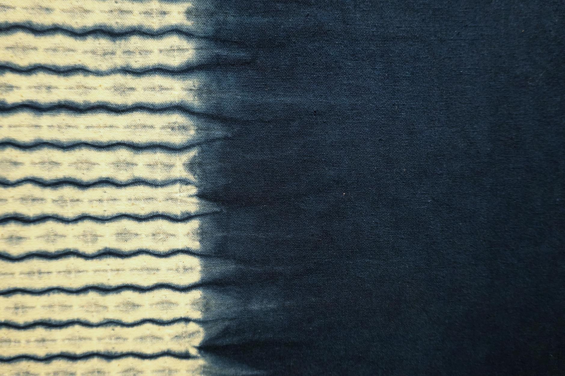 Close-up of indigo-dyed fabric featuring a wave pattern transitioning from light to dark blue.