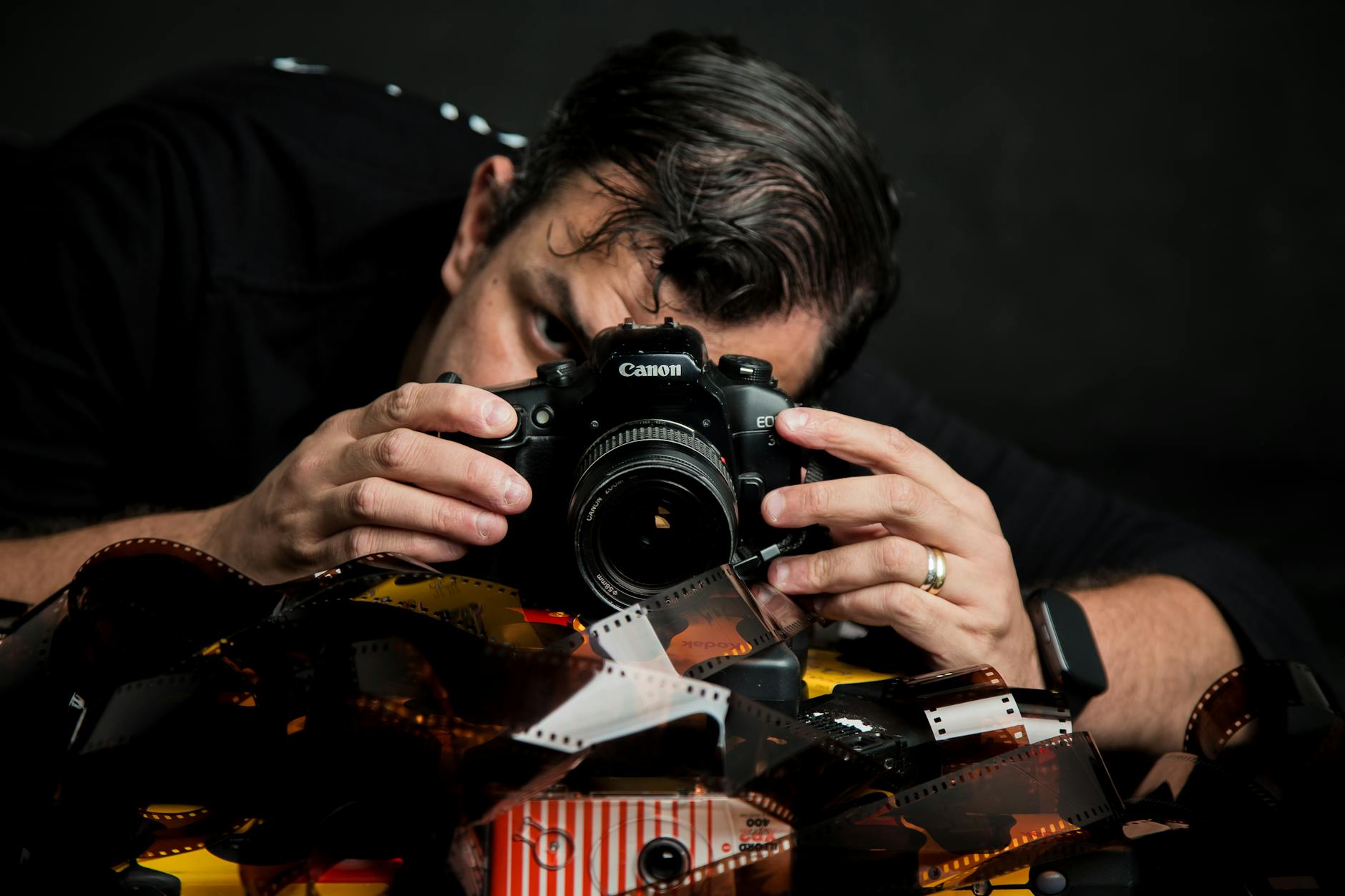Queer Lisboa: sessões que costumam esgotar — como não perder as melhores 4 Close-up of photographer with camera among film rolls, highlighting analog photography in Lisboa, Portugal.