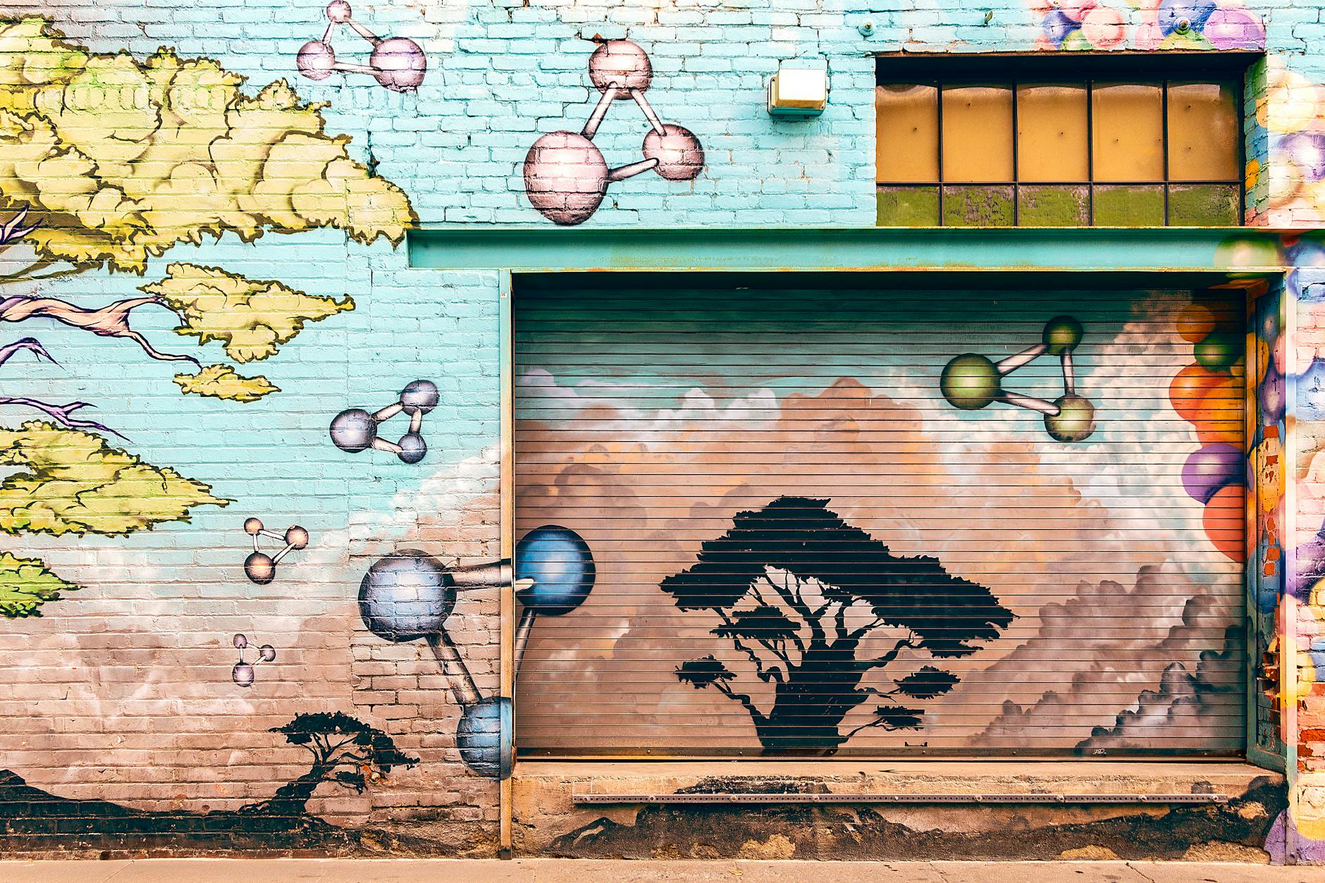 Colorful mural on a brick wall in Pasadena featuring trees and molecular shapes.