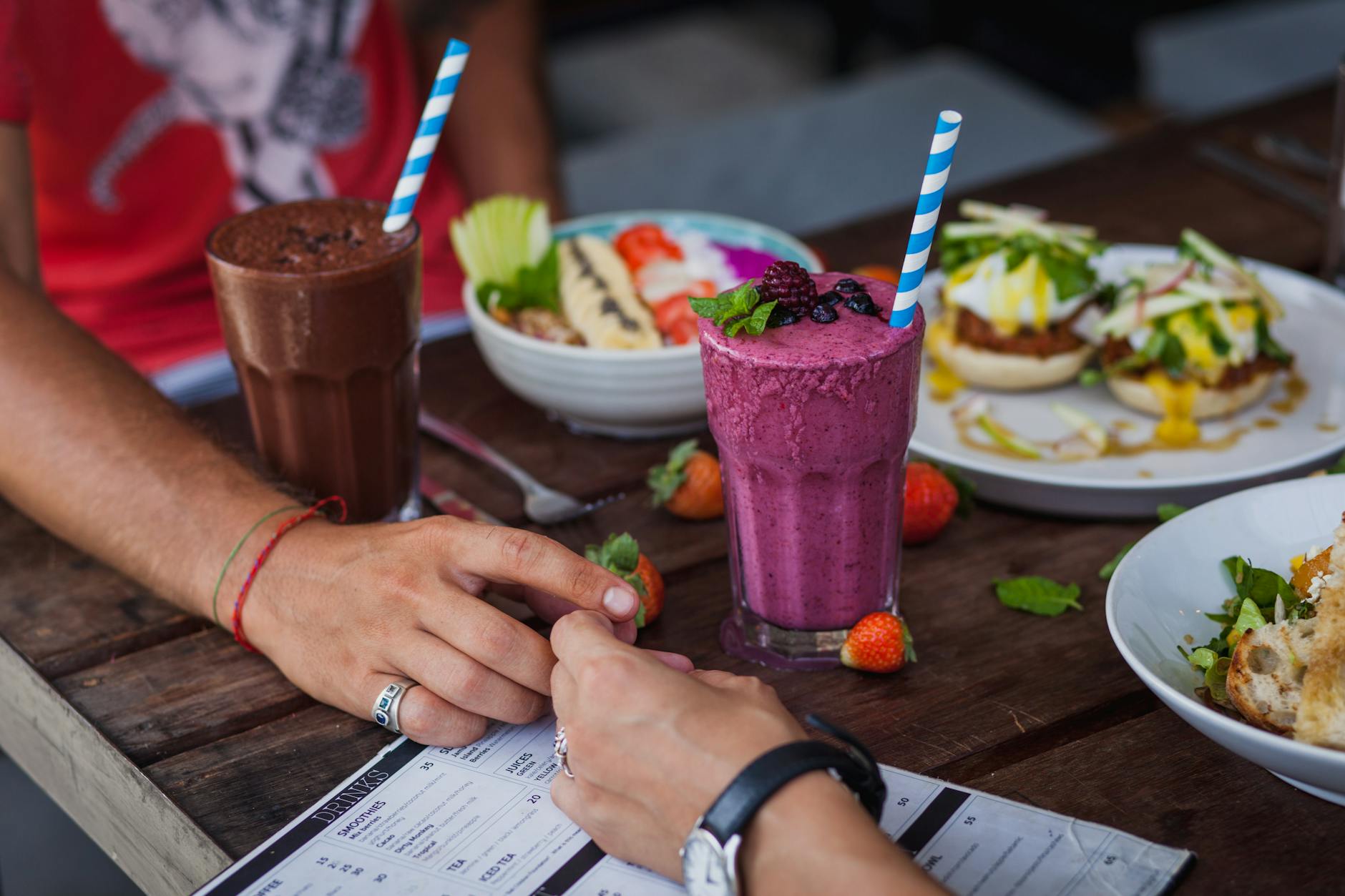 Couple enjoying a brunch date with smoothies, fresh fruit, and gourmet dishes outdoors.