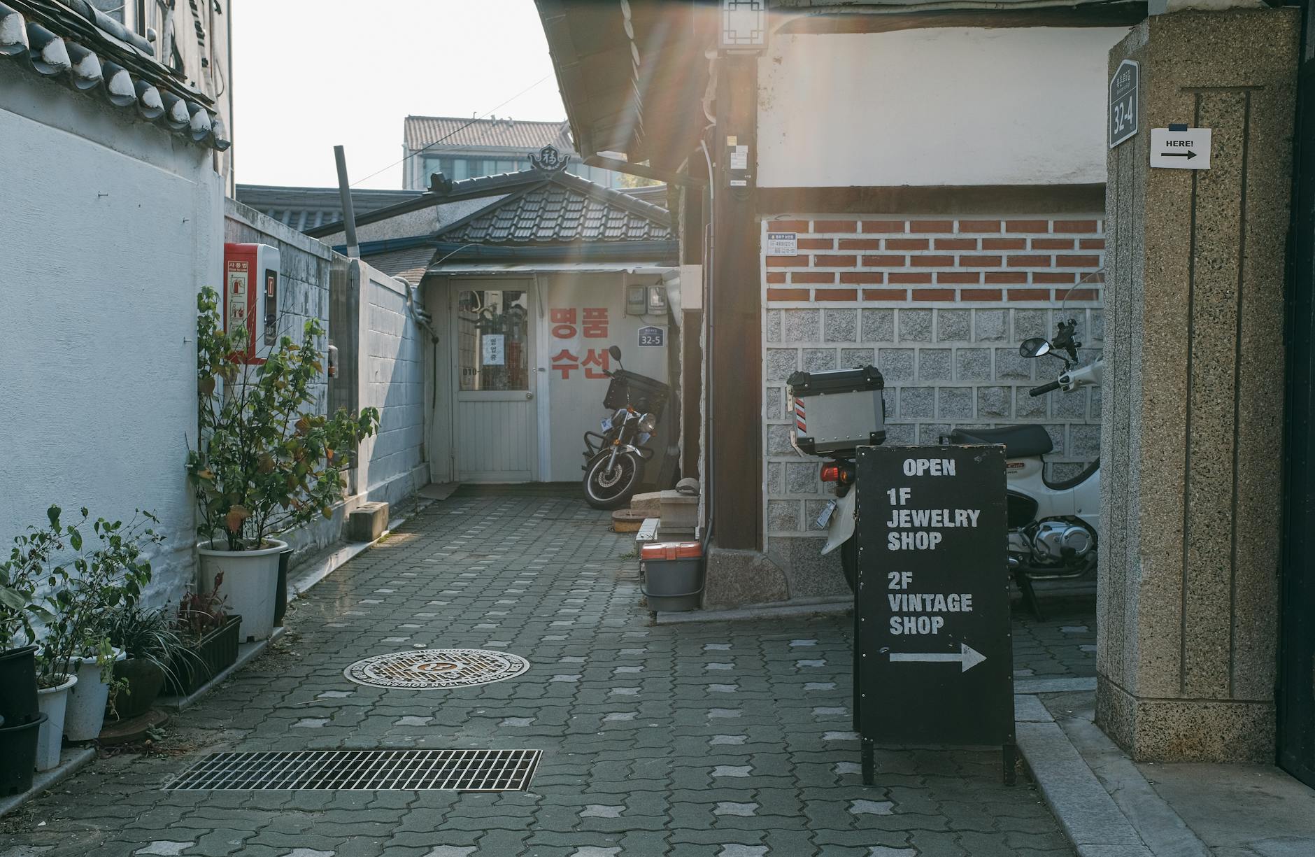 Graça Sem Pressa: Cafés, Miradouros E Ruas Bonitas 5 Cozy alley in Seoul with parked motorcycles and shop signs, evoking urban charm.