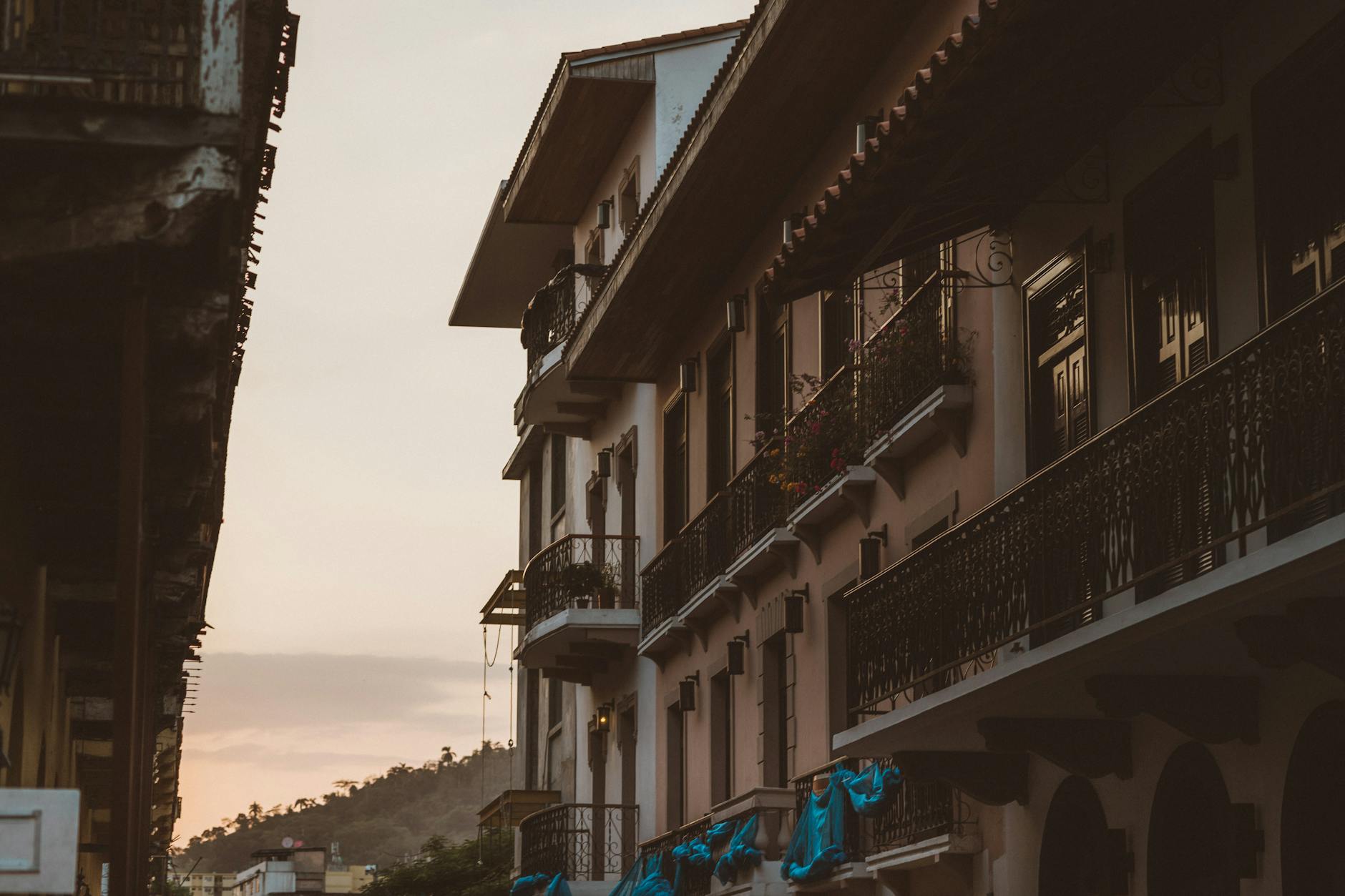 Elegant colonial-style buildings line a quiet street, captured in warm evening light.