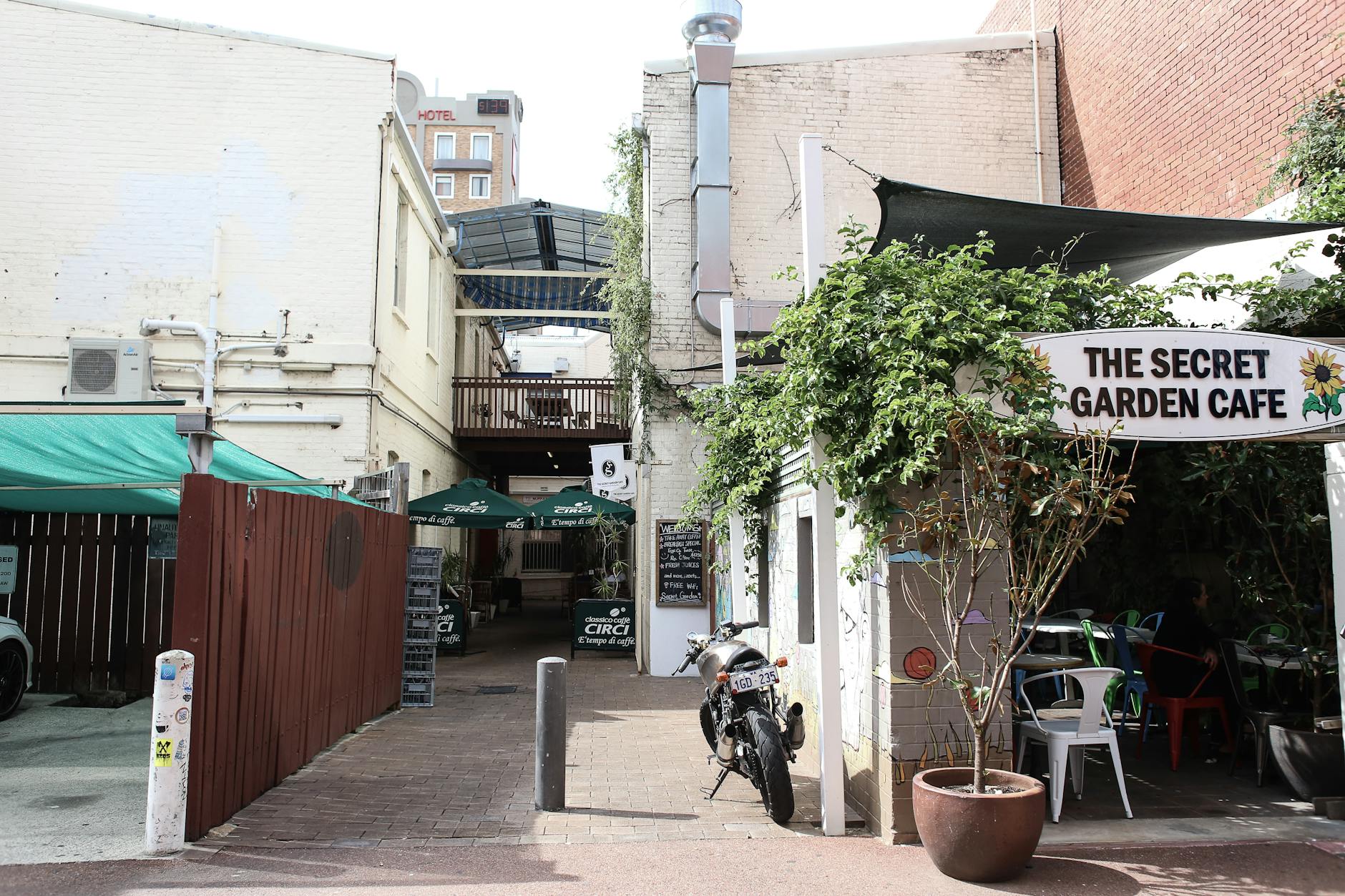 Os Melhores “Hidden Gems” Em Lisboa: 30 Lugares Que Surpreendem 4 Explore the rustic charm of a hidden cafe in a narrow city alley, complete with greenery and a parked motorcycle.