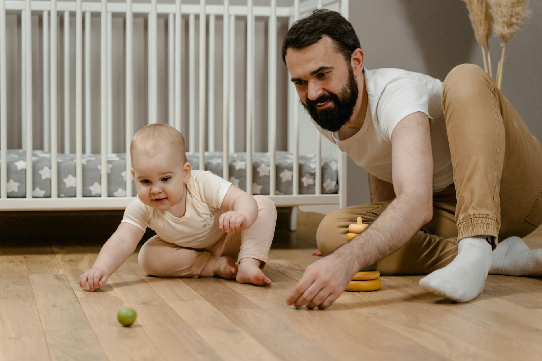 Father bonding with his baby in a cozy nursery, enjoying quality playtime on a wooden floor.
