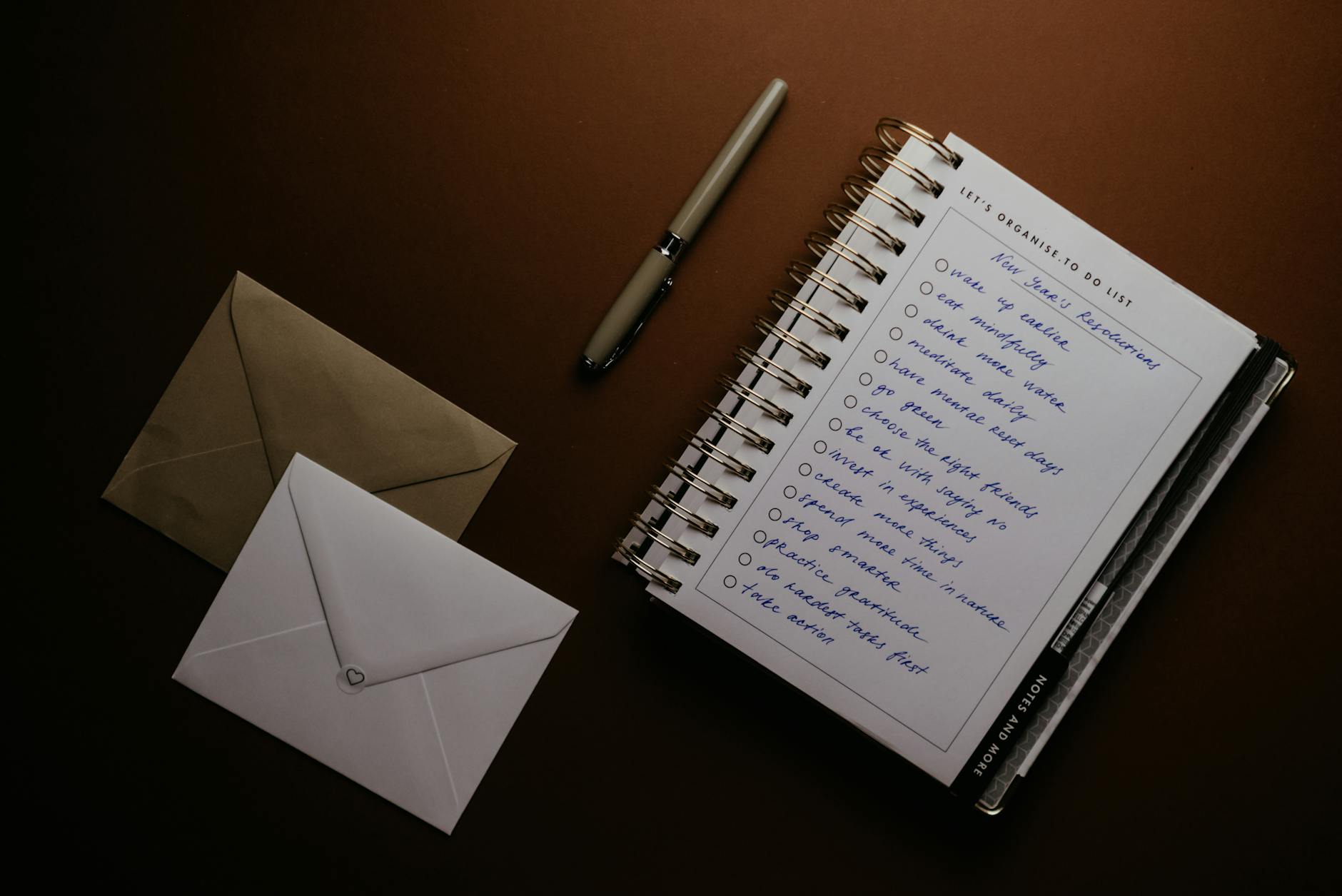 Flat lay of a to-do list, pen, and envelopes on a brown surface, ideal for planning themes.