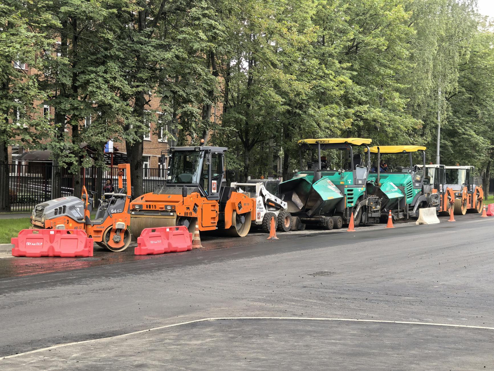 Heavy machinery for roadwork lined up on an urban street during daytime construction.