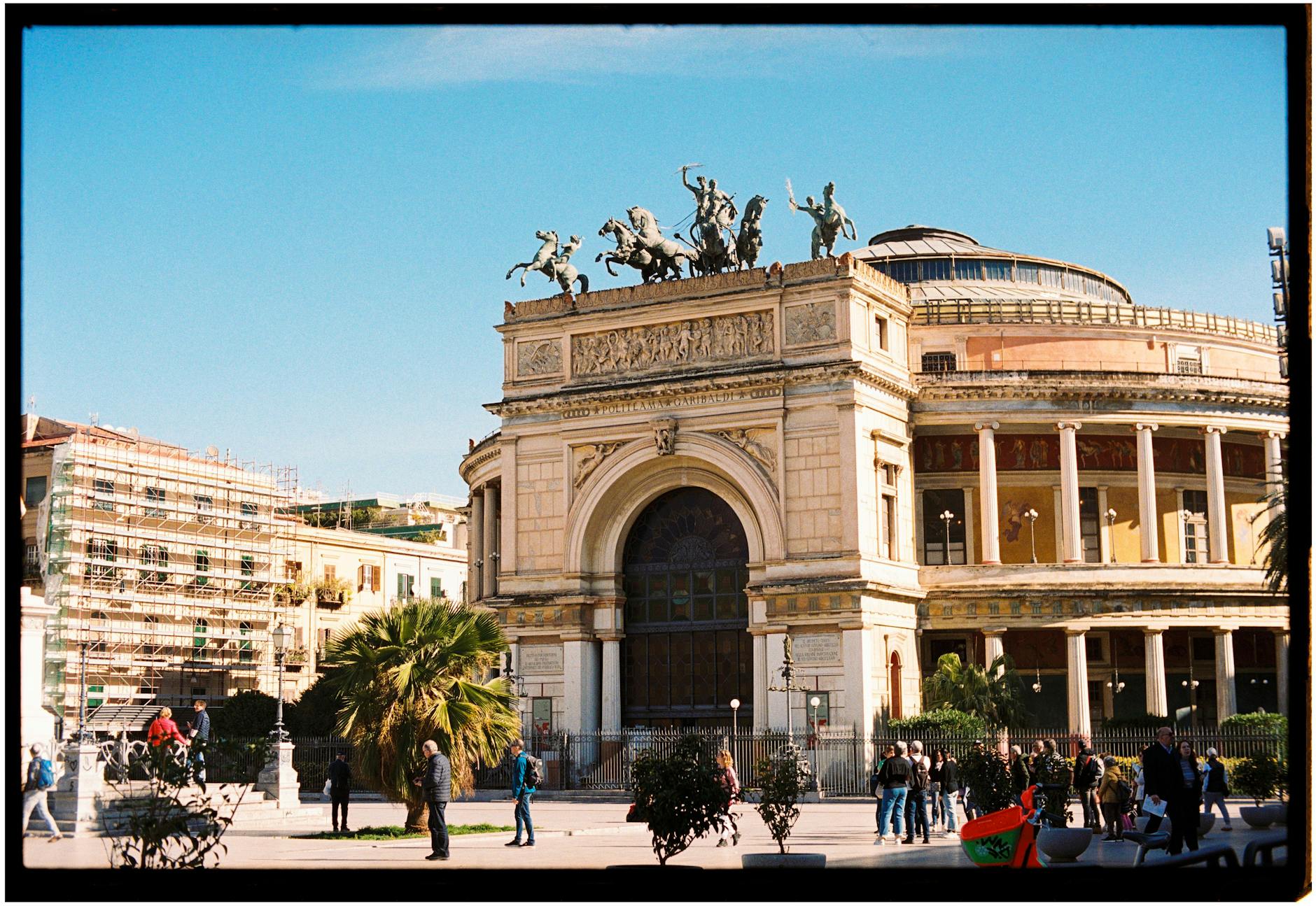 Historic Teatro Politeama in Palermo, Italy, captured on a sunny day with vibrant street activity.